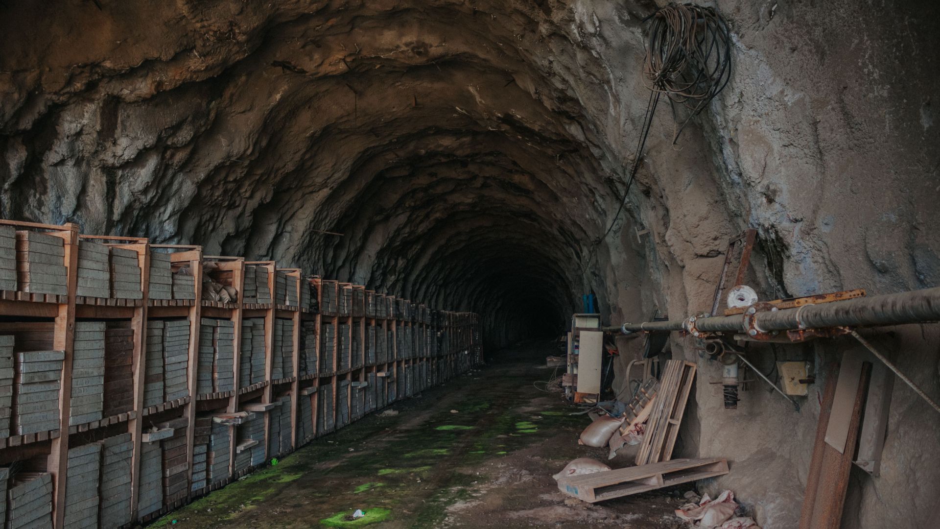 An underground tunnel with stored bricks and industrial equipment, evoking a sense of mystery.