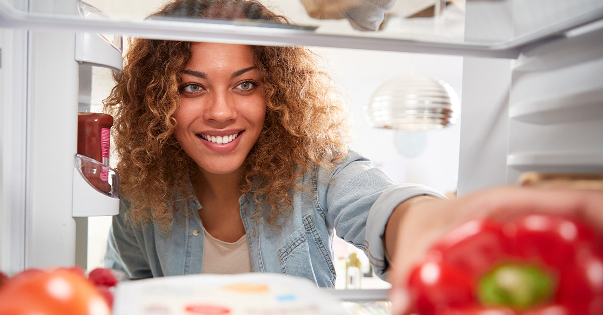 Woman looking in her fridge, reaching for some food.
