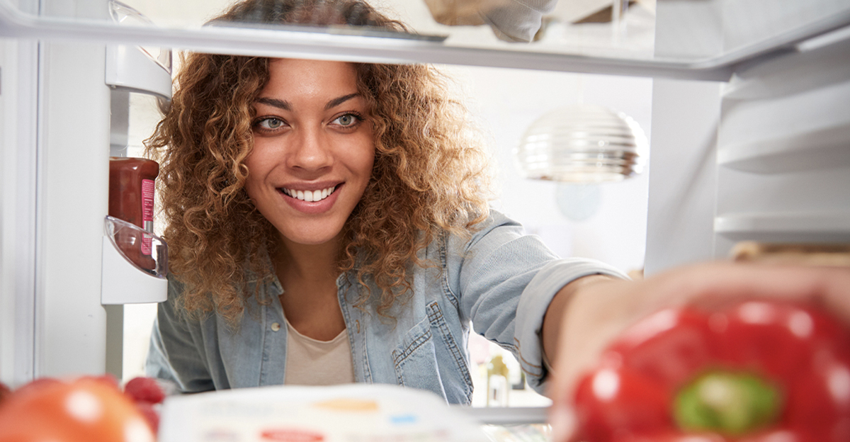 Woman looking in her fridge, reaching for some food.