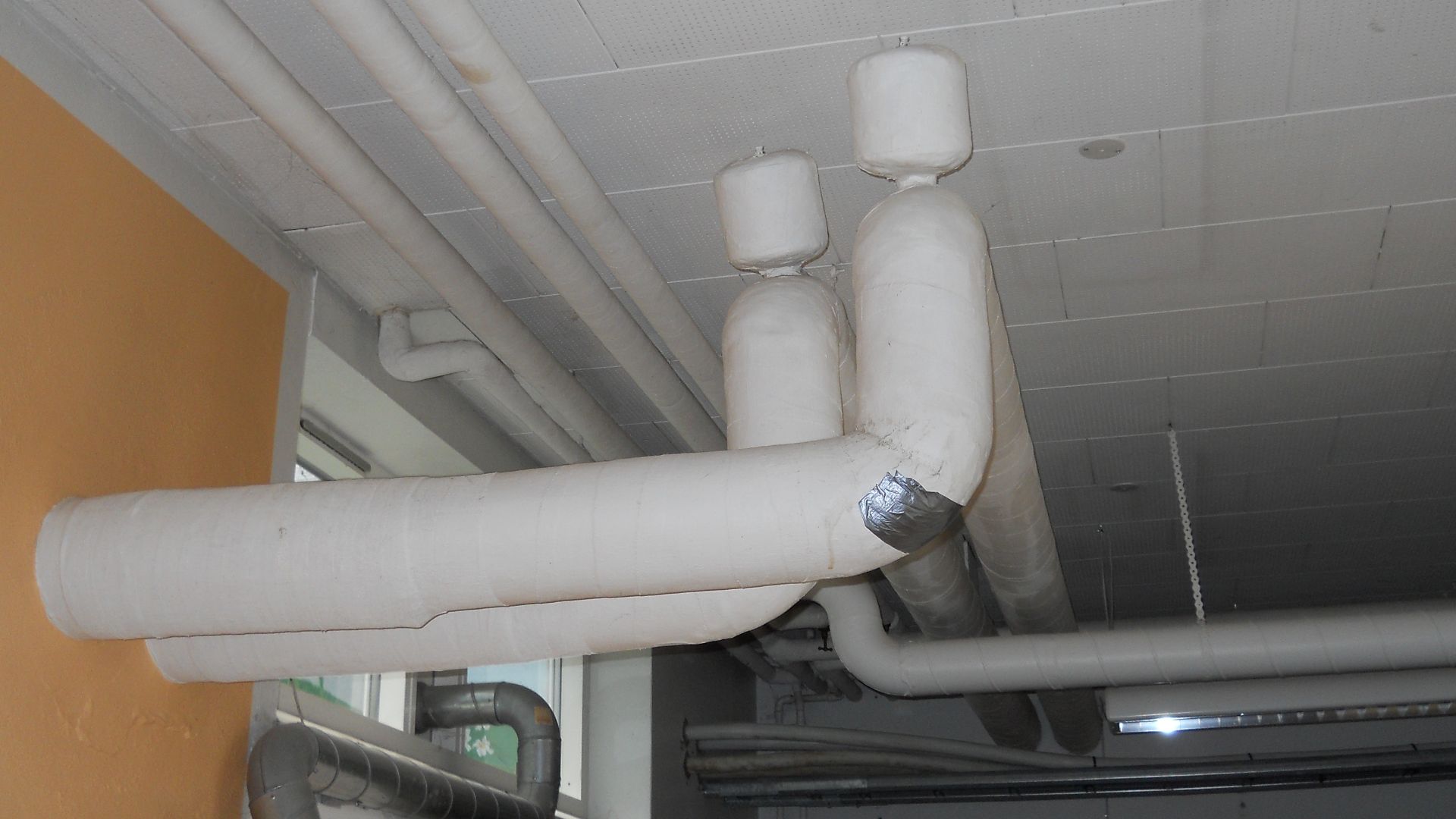 Thermal insulation of a pipe. The insulation is made from asbestos fibres.