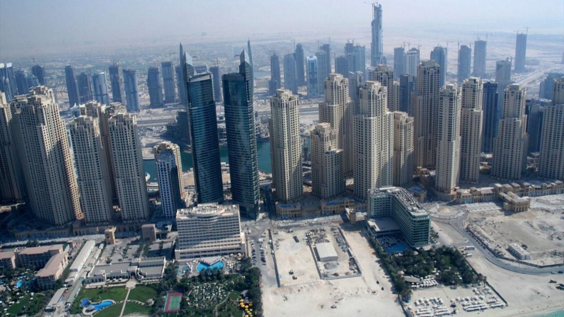 This is a photo showing Dubai Marina (in the front) and Jumeirah Lake Towers (in the back) in Dubai, United Arab Emirates. The beige buildings in the front are apart of Jumeirah Beach Residence, a sub-development in Dubai Marina. This photo was taken fr