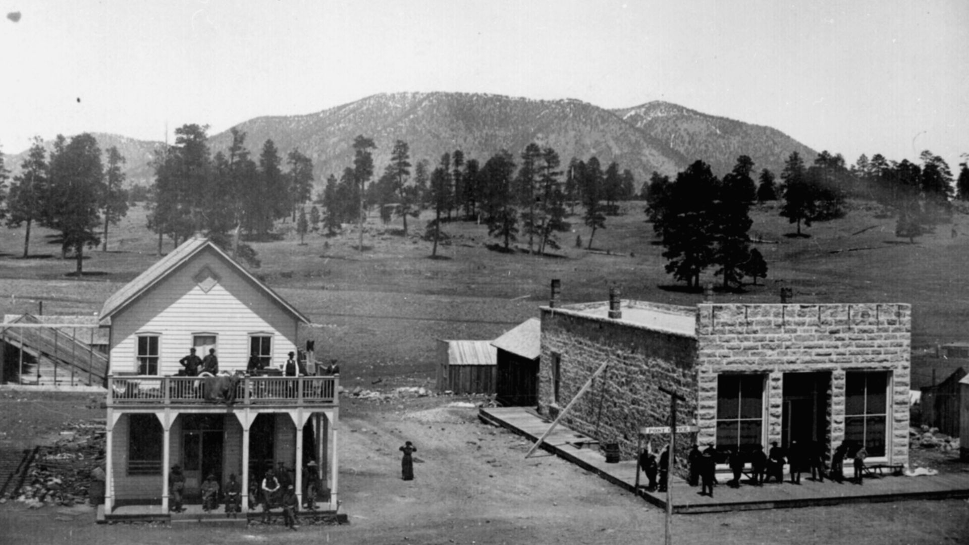 Flagstaff. Street view of post office, other buildings, and people, with mountains in background, ca. 1899.