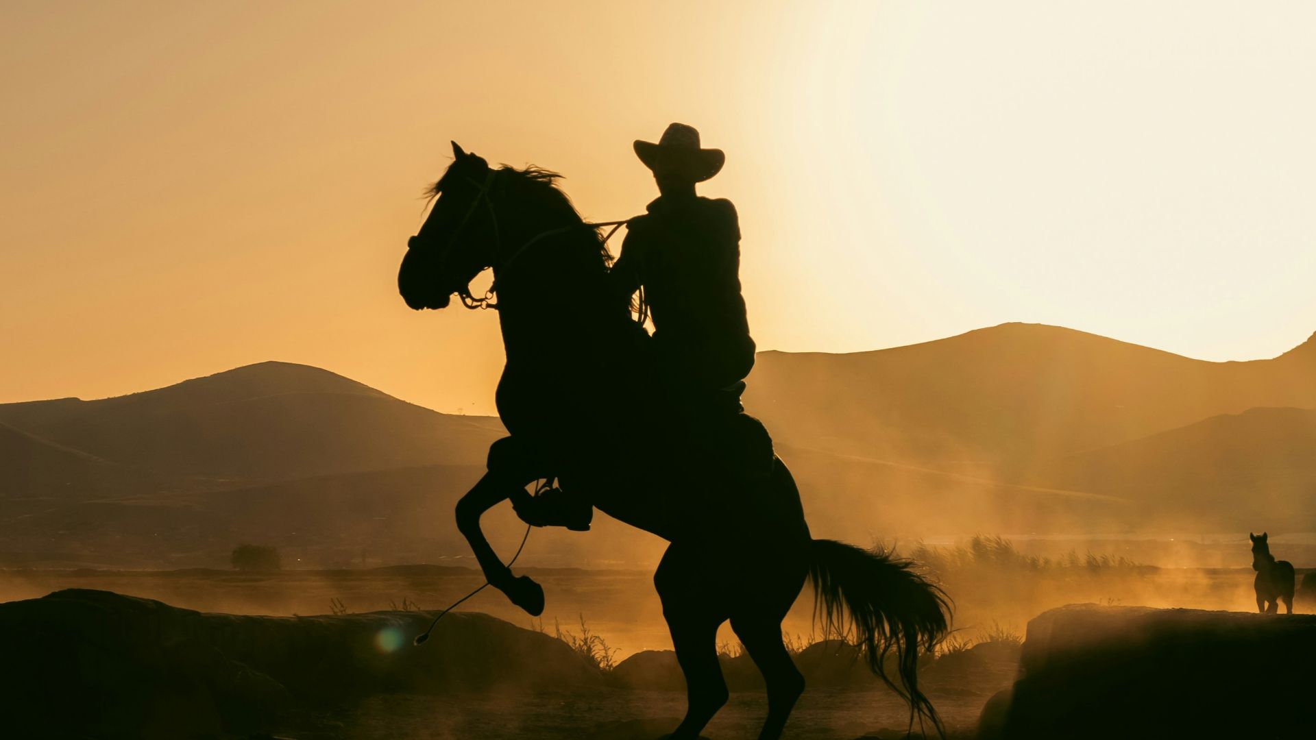 A silhouette of a man riding a horse at sunset
