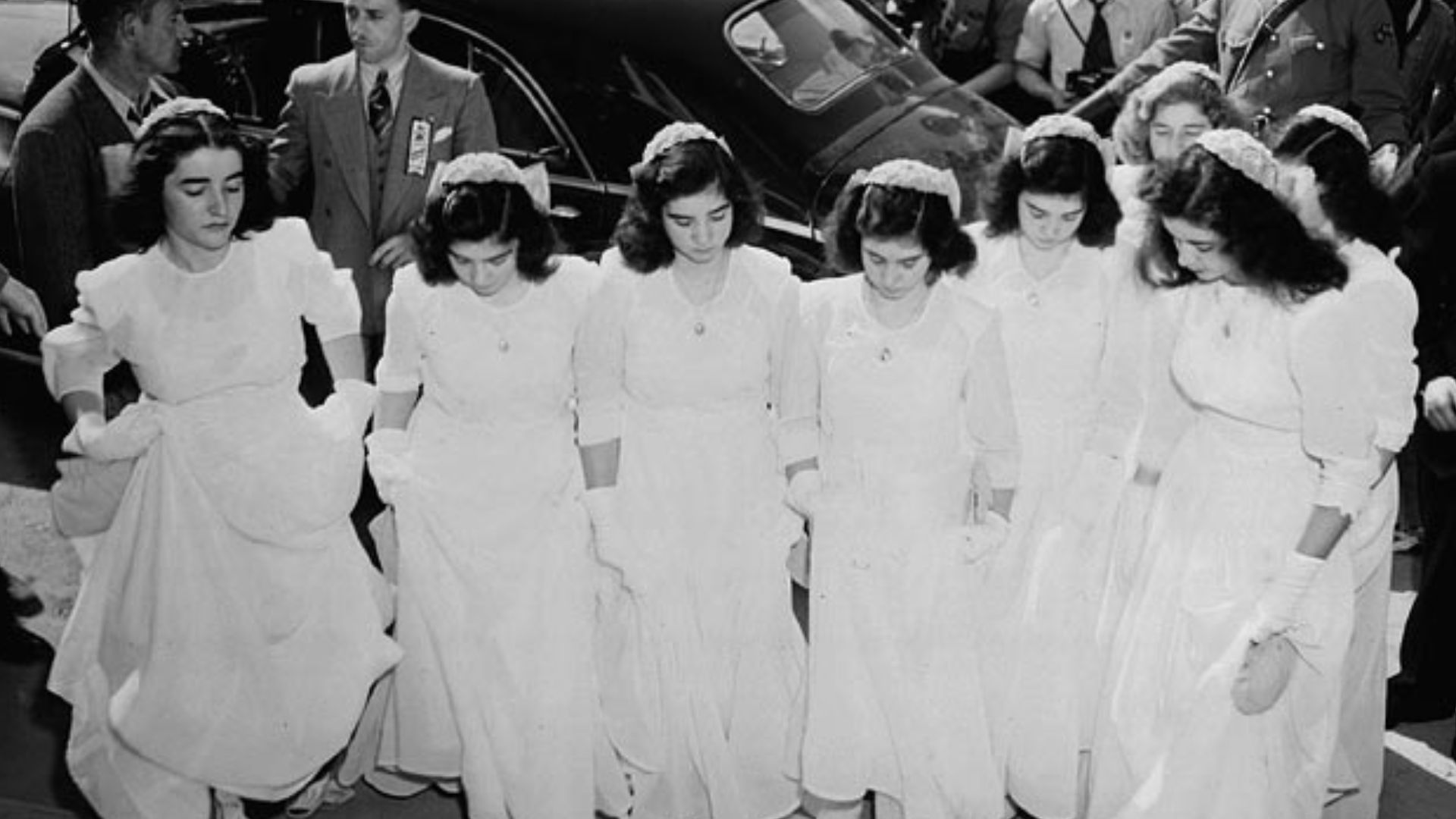 The Dionne quintuplets and their sisters arrive at Lansdowne Park to take part in a program of religious music during the Marian Congress at which 250,000 Catholics prayed for peace and celebrated the centenary of the Ottawa archdiocese.