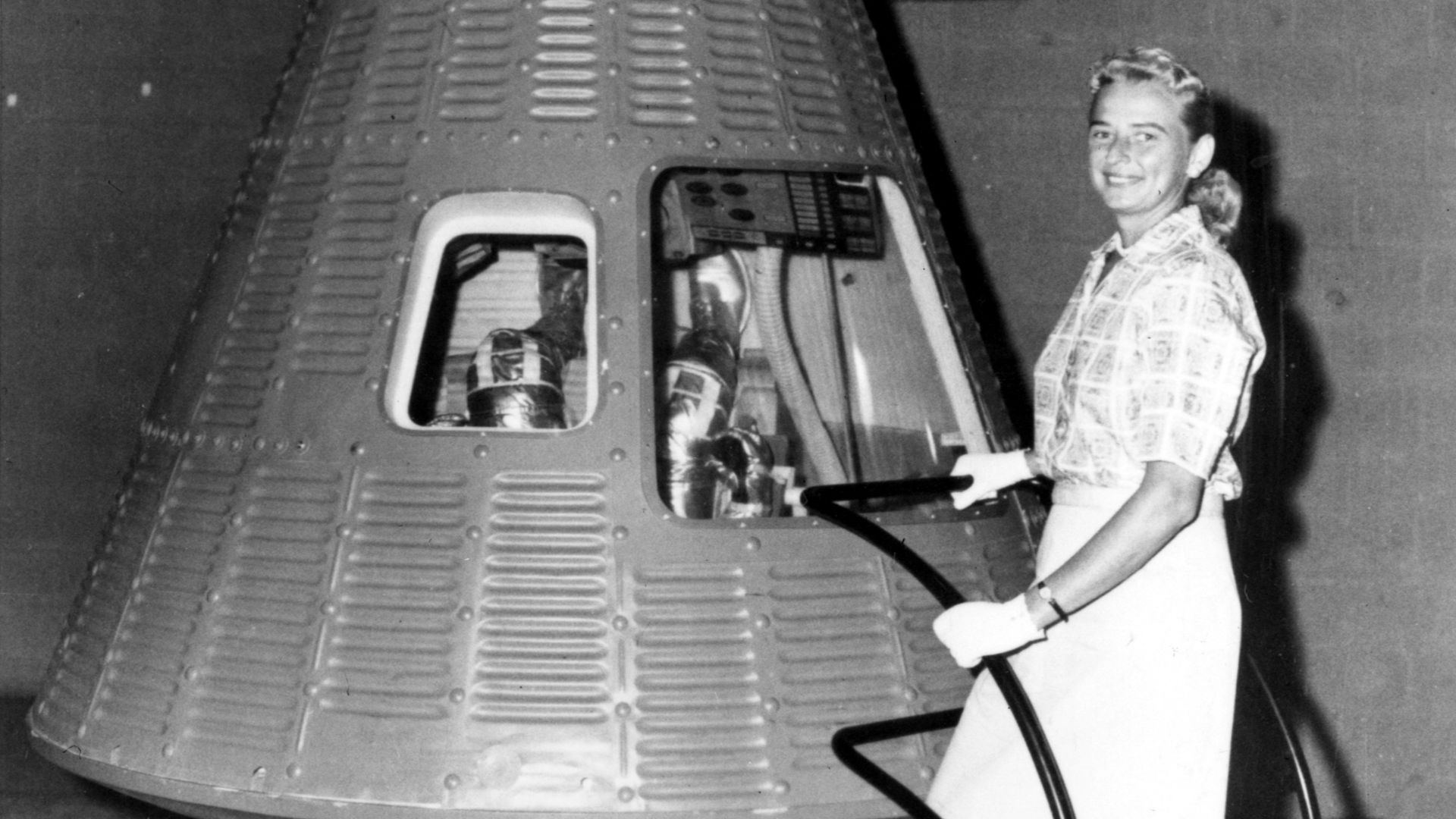 Jerrie Cobb poses next to a Mercury spaceship capsule. Although she never flew in space, Cobb, along with twenty-four other women, underwent physical tests similar to those taken by the Mercury astronauts with the belief that she might become an astronaut
