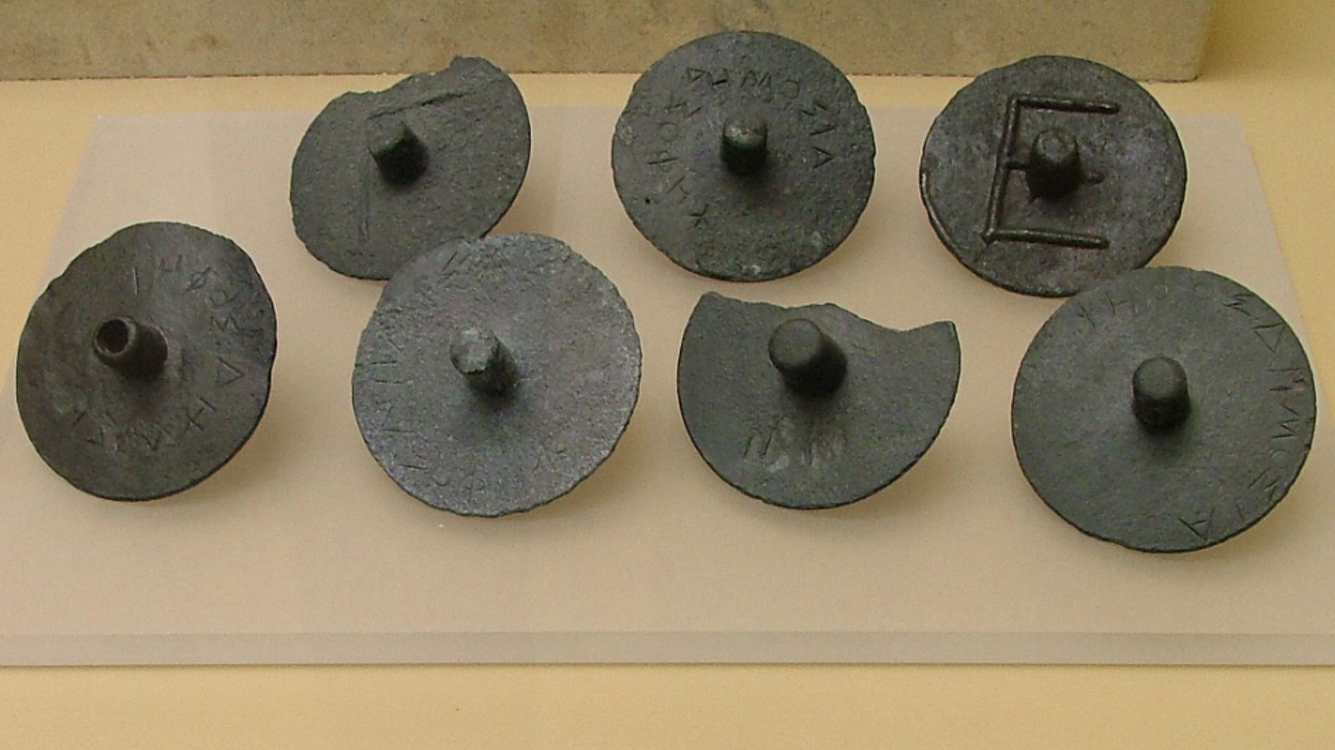 These disks were used to cast a juror's vote on a case. They would cover up the top when submitting their secret vote, which if closed meant innocent and open (left bottom) meant guilty, or there was a hole in the soul. Ca. 300 BC. Ancient Agora Museum in