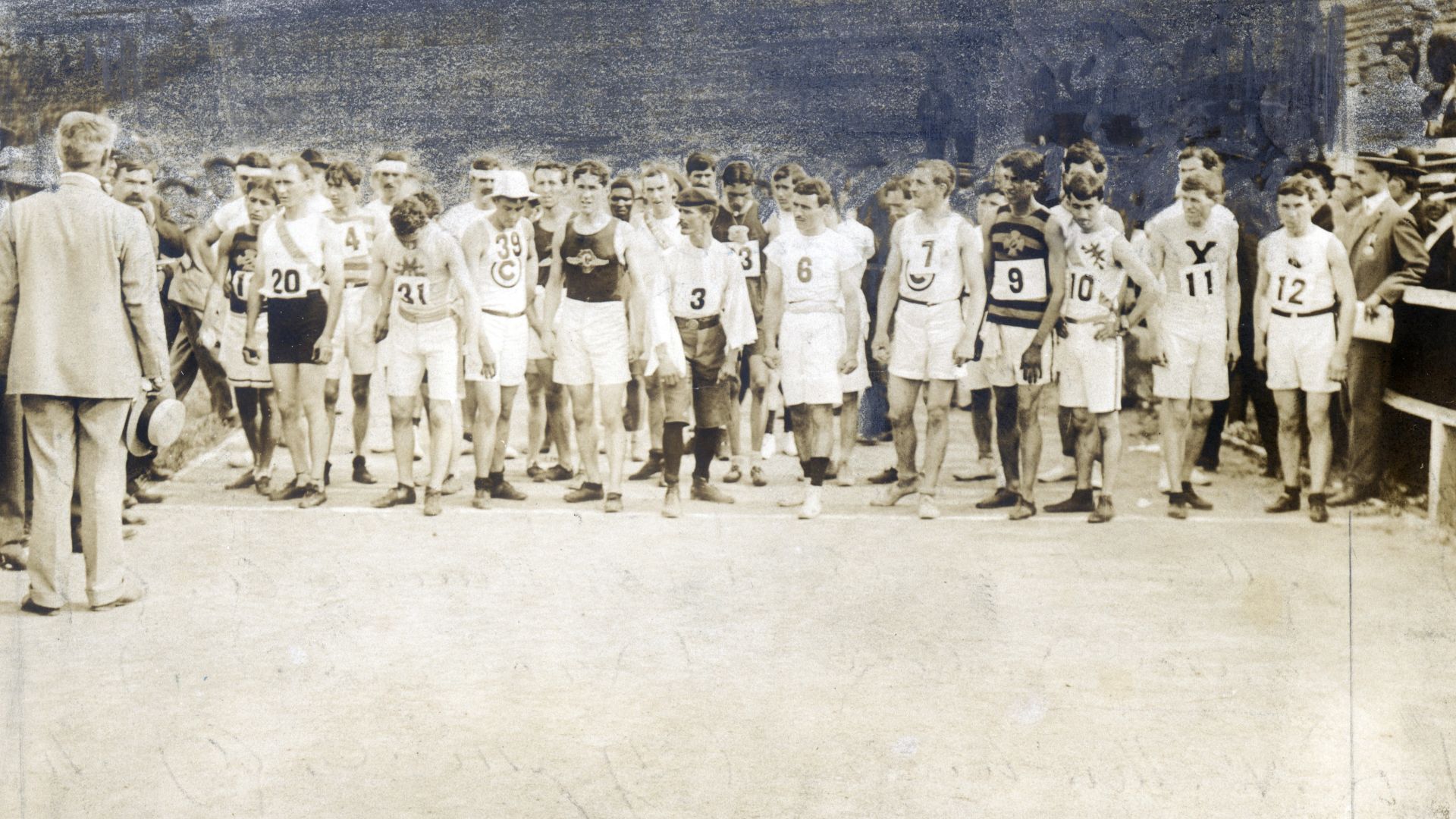 Thomas Hicks (20), Fred Longm (31), S. H. Holt (39), Felix Caravajal (3), Christos D. Zehouritis (6), Albert L. Cory (7), Frank Pierce (9), S. A. Mellor (10), Edward P. Car (11)Title: 1904 Olympics: Runners lined up at start of Marathon Race, receiving in
