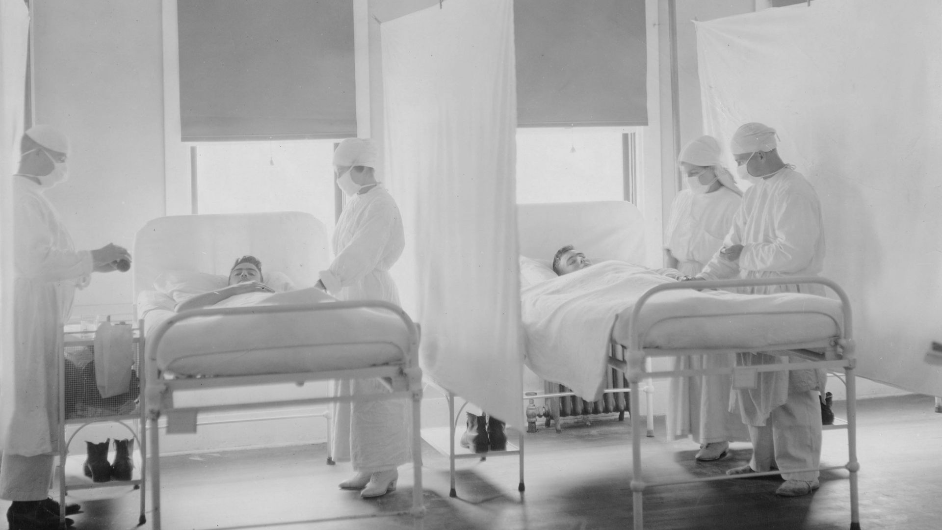 Medical staff attending to patients in hospital beds.