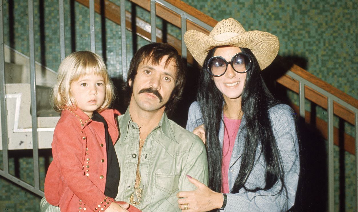 American singers and actors Sonny and Cher Bono pose with their daughter Chastity in front of a staircase, March 1, 1973. 