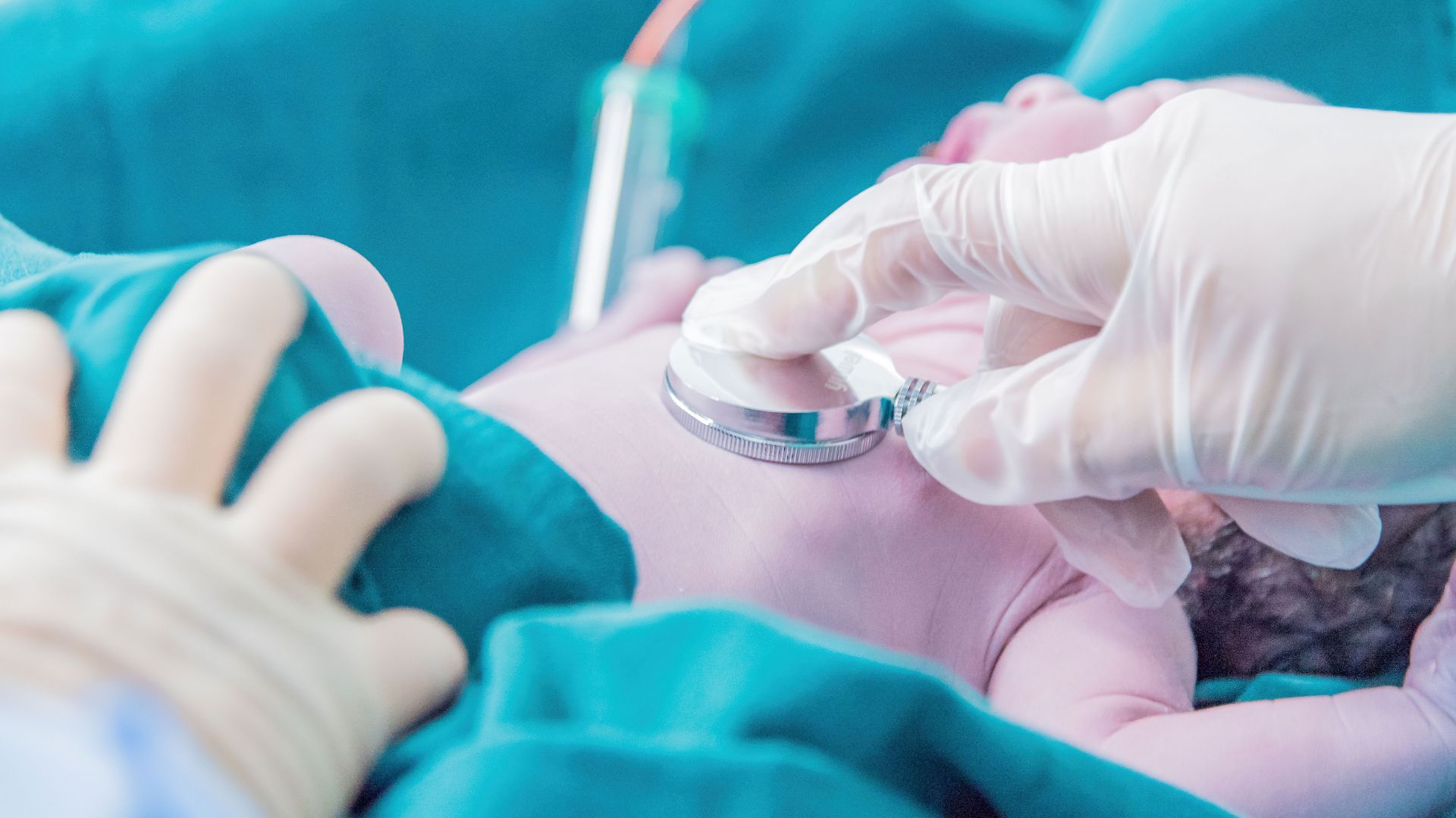 Medical professional examining a newborn baby with a stethoscope in a hospital setting.