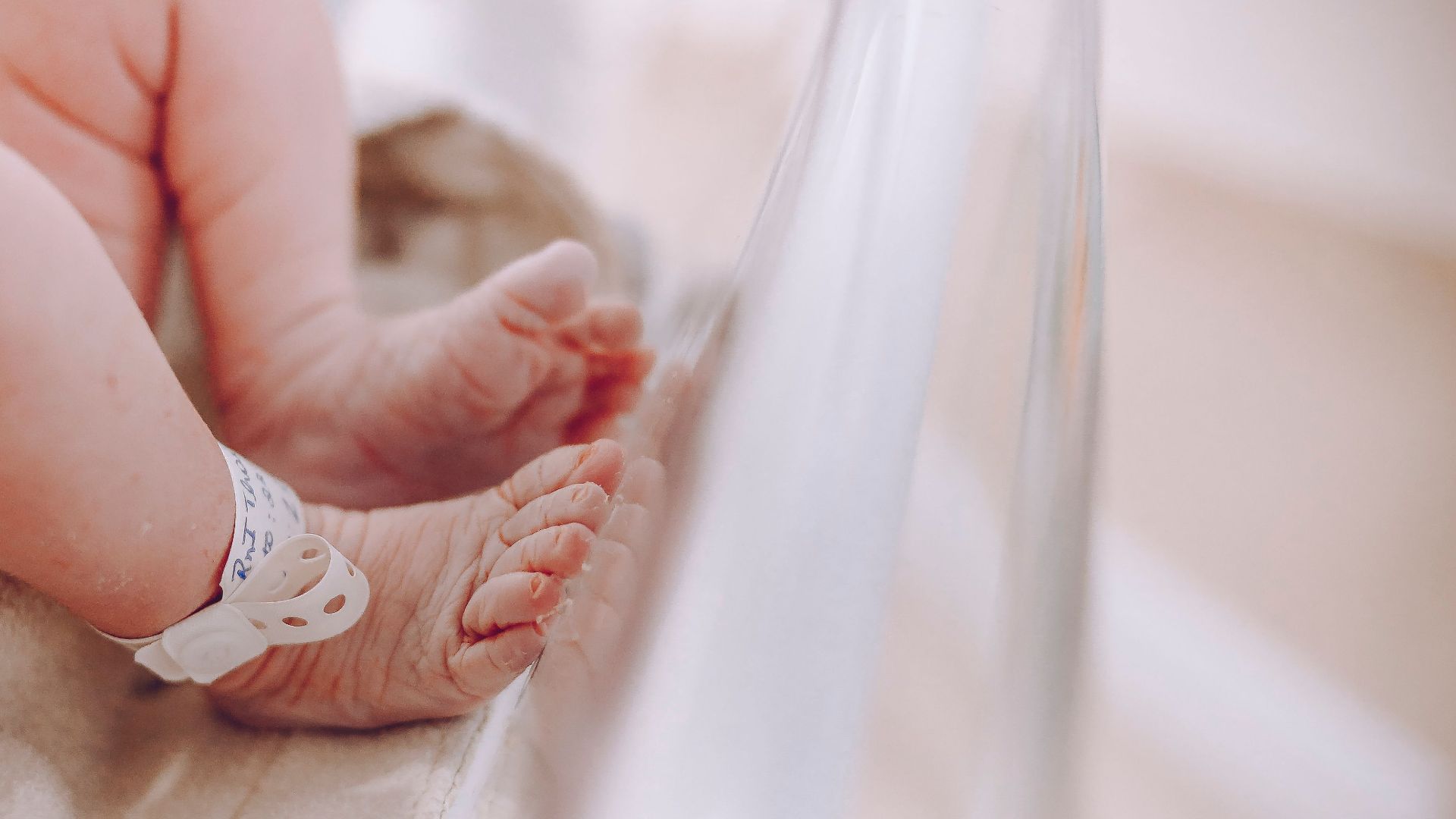 Close-up of newborn baby feet with hospital ID bracelet, symbolizing new beginnings.