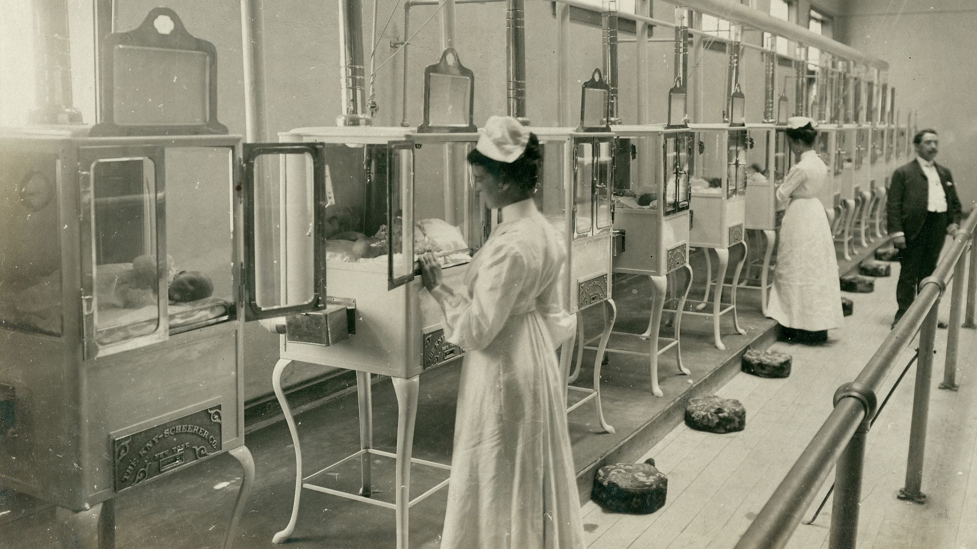 Title: Manager, Mr. E.M. Bayliss and nurses attending babies in the Baby Incubator exhibit on the Pike at the 1904 World's Fair.