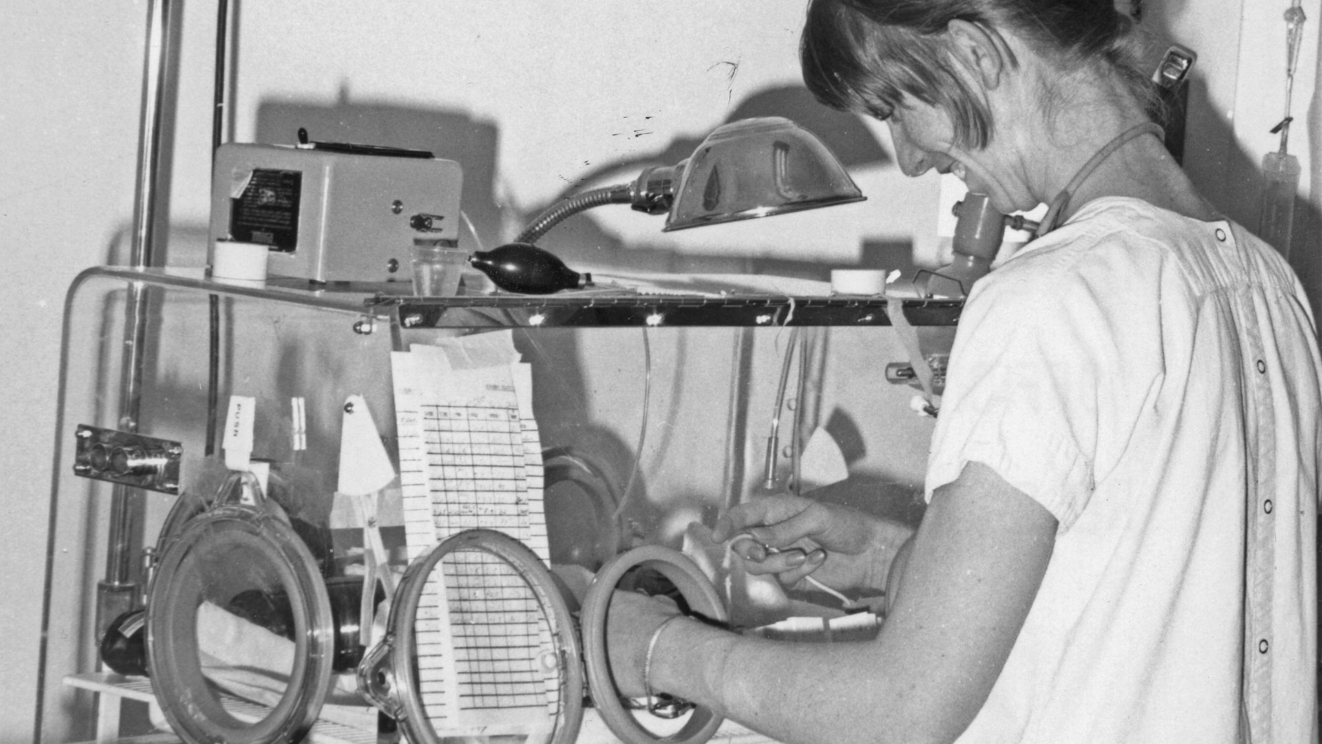 Nurse tending to infant in incubator