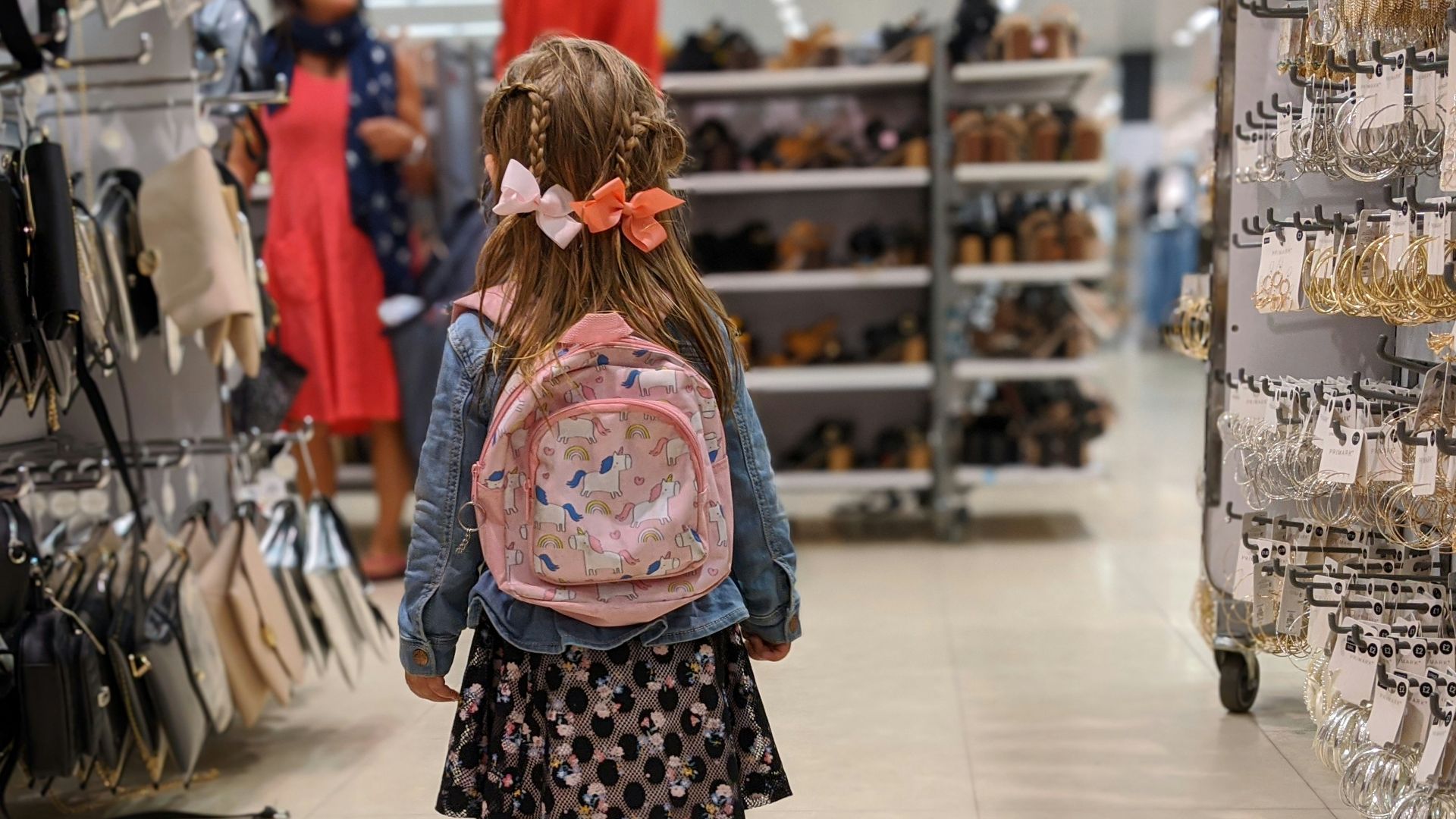 girl in pink and blue floral dress standing on white floor tiles