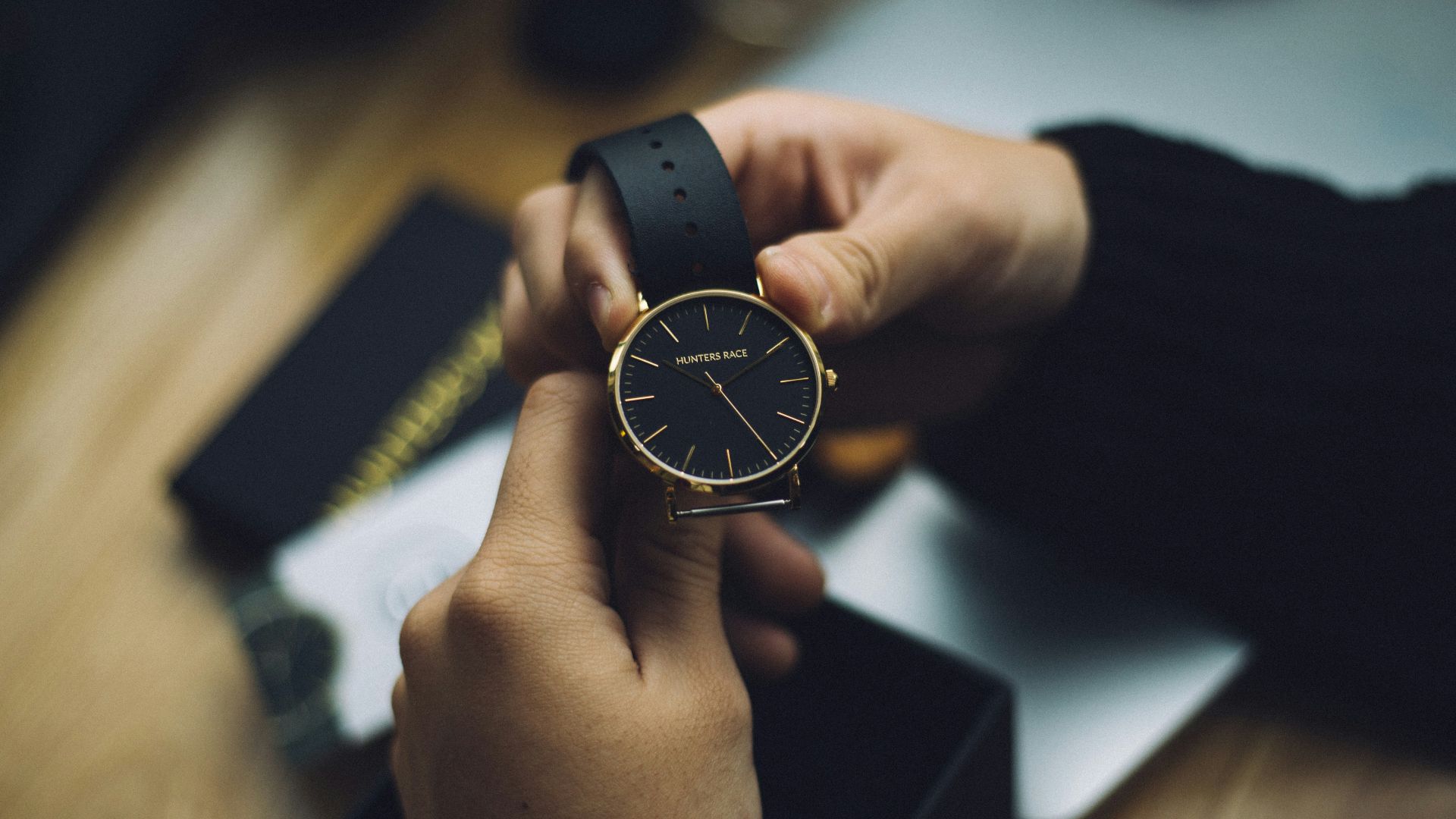 person holding gold-colored analog watch with black strap