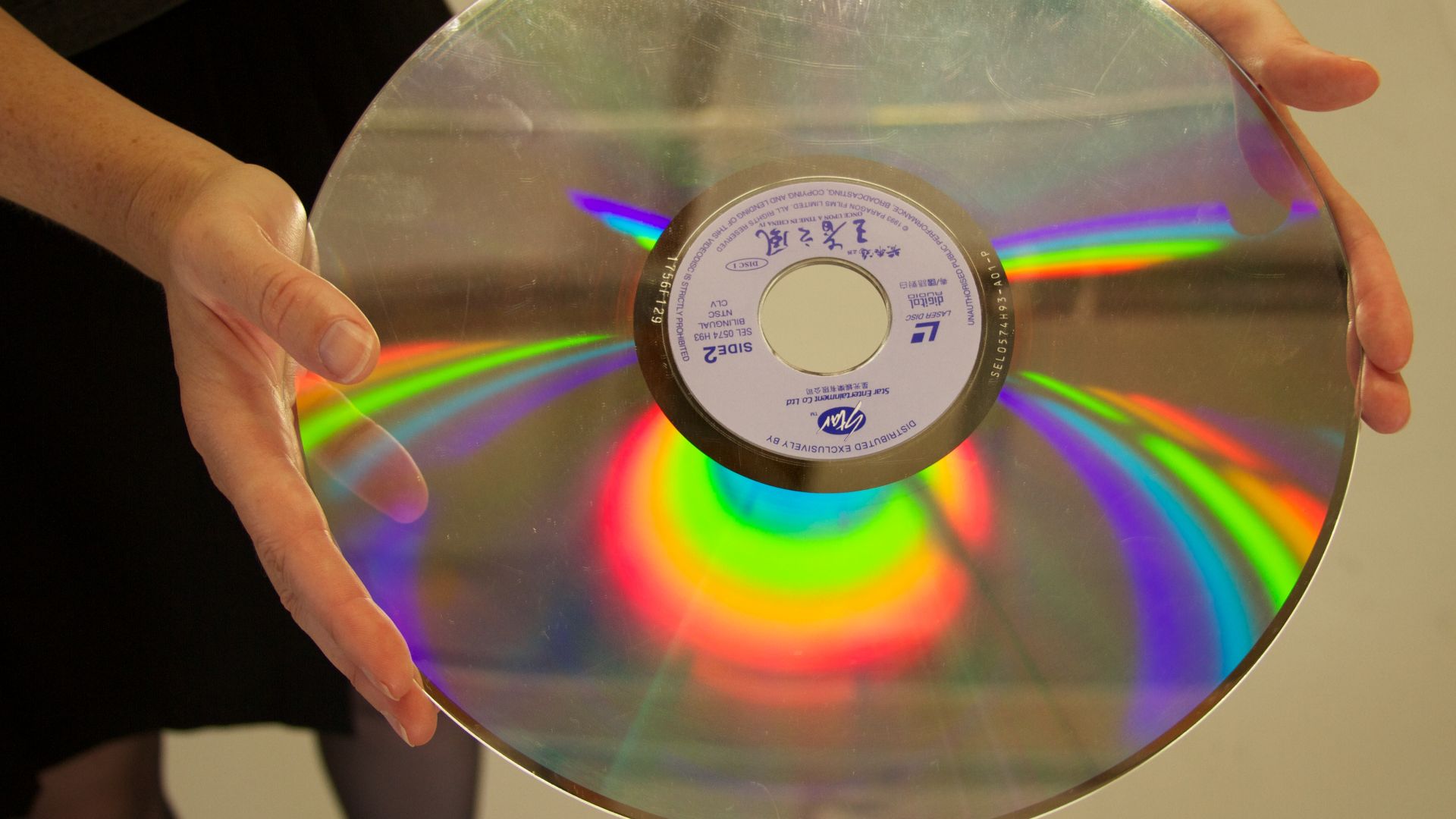 12 inch LaserDisc being held by a woman, giving an idea of the size of the disc itself.