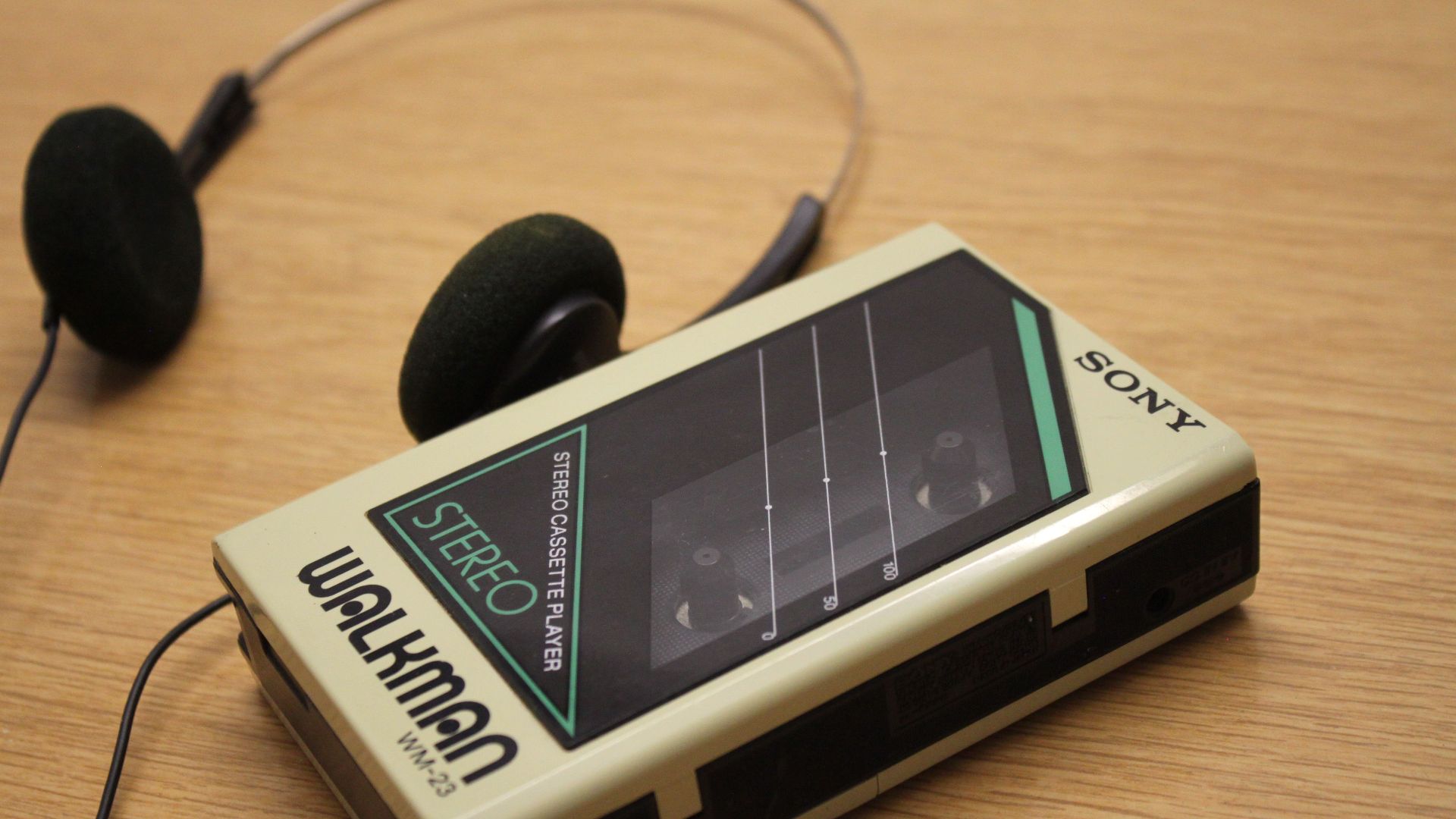 Classic Sony Walkman stereo cassette player with retro headphones on wooden surface.