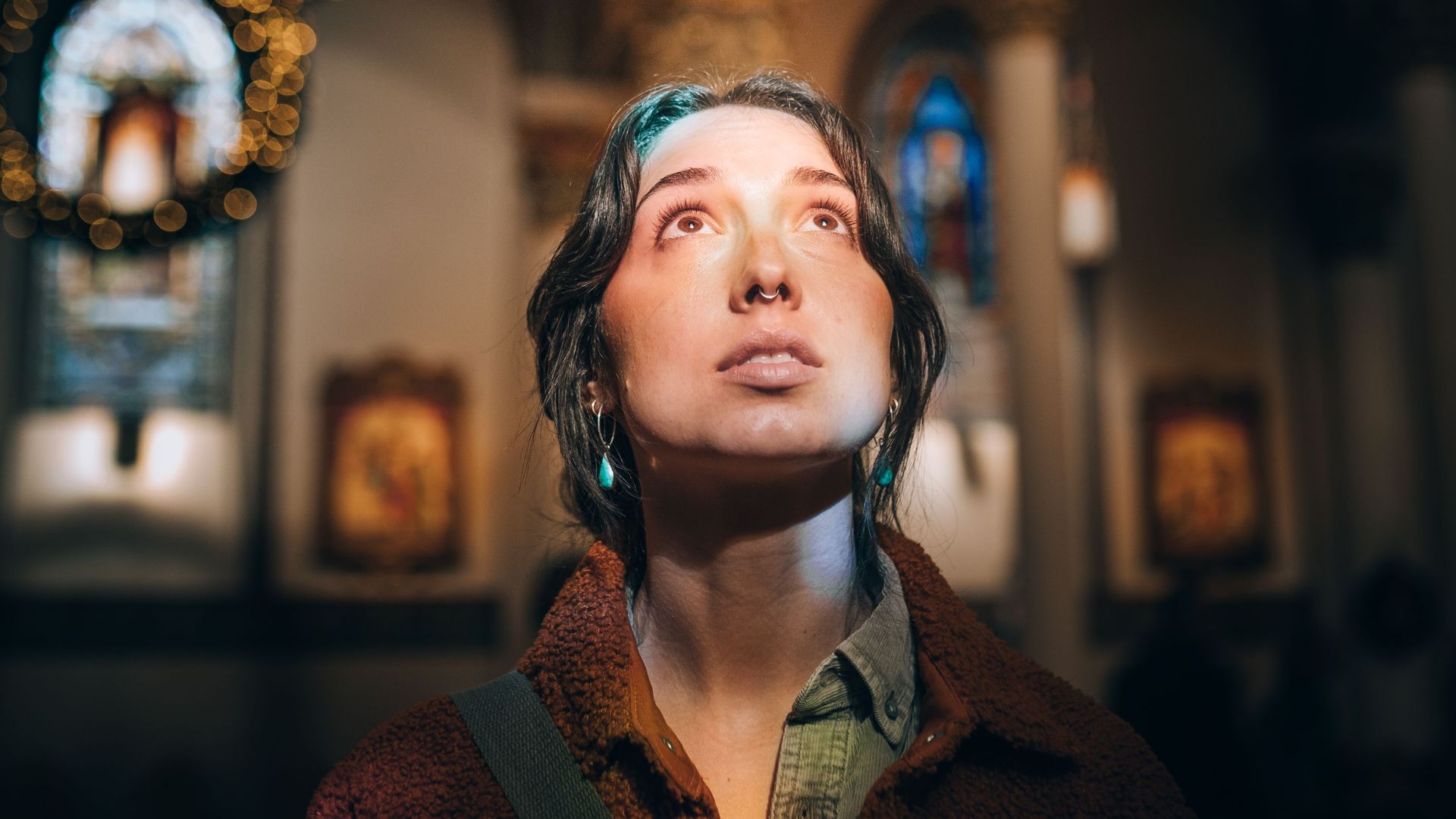 Woman gazes upwards in a beautifully lit church, evoking a sense of peace and reverence.