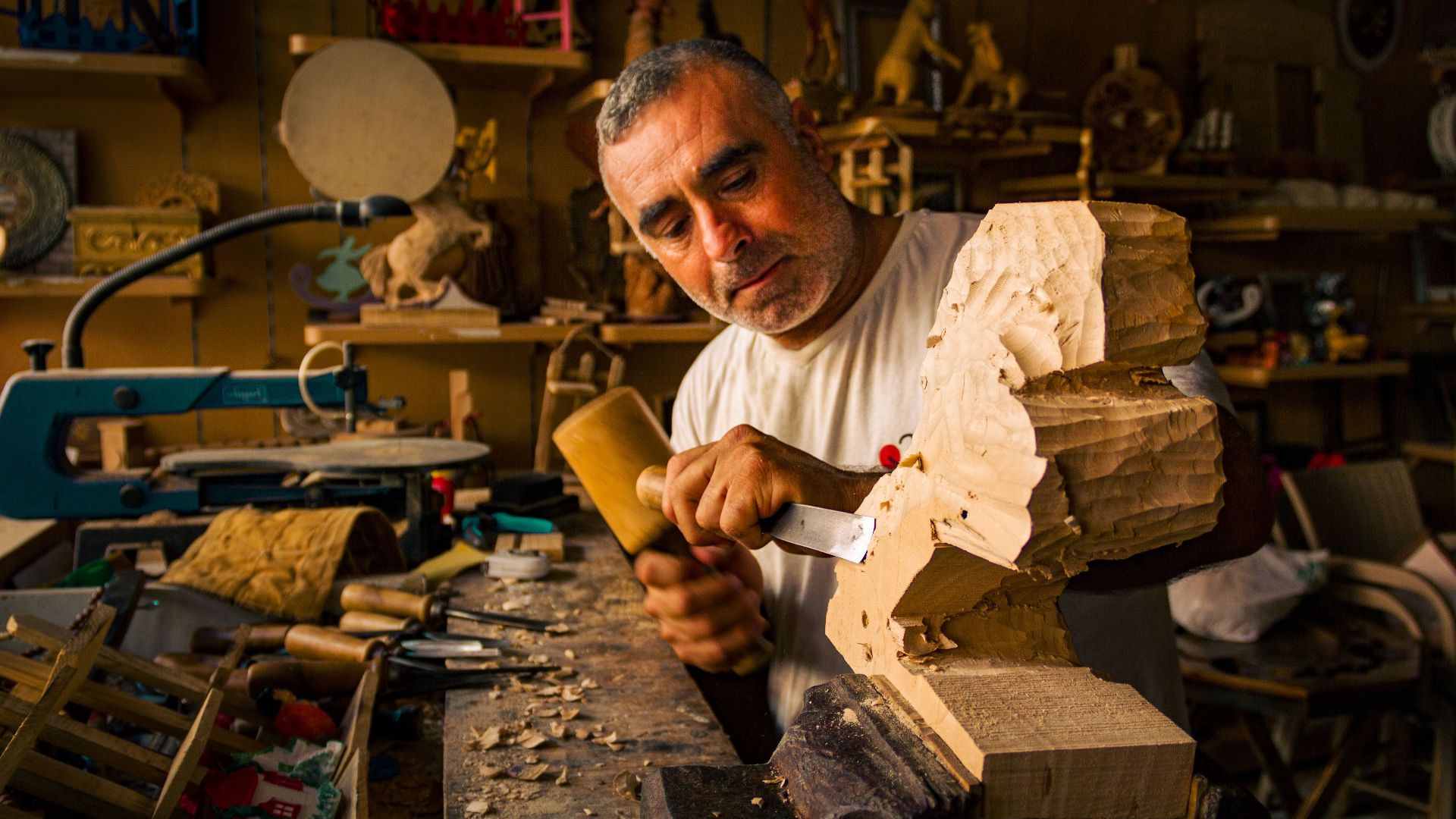 Artisan crafting a wooden sculpture in a well-equipped workshop, showcasing expert woodworking skills.