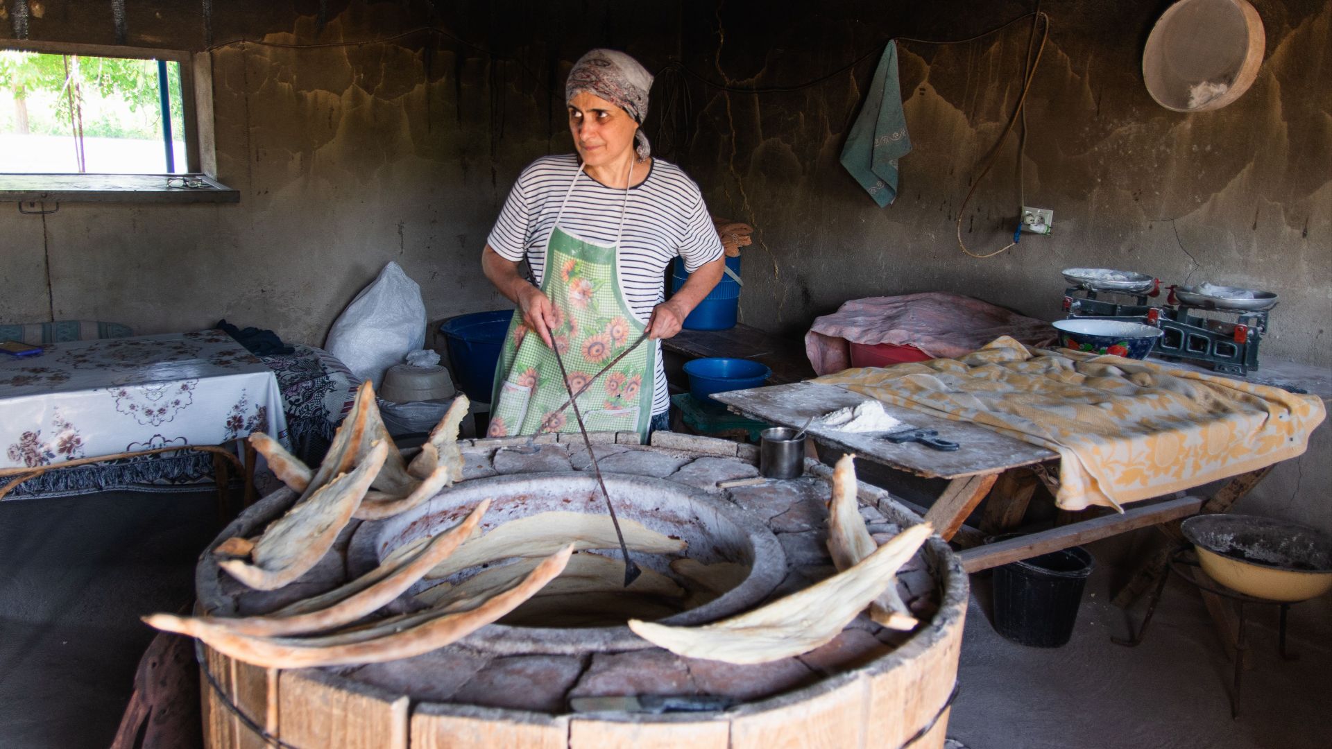 Woman baking traditional bread in a rustic kitchen with a wood-fired oven.