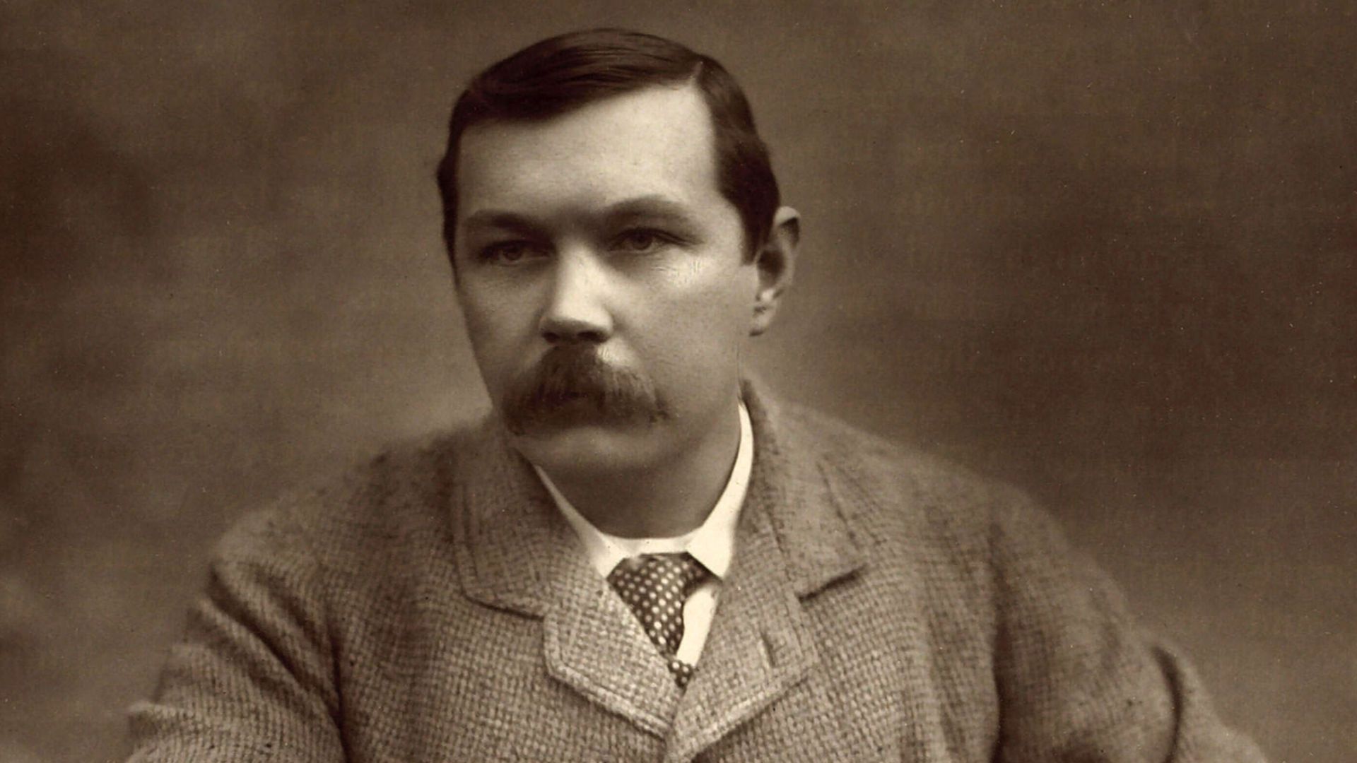 Black and white photograph of Sir Arthur Ignatius Conan Doyle by the English photographer Herbert Rose Barraud. Carbon print on card mount. 9 3/4 in. x 7 1/8 in.