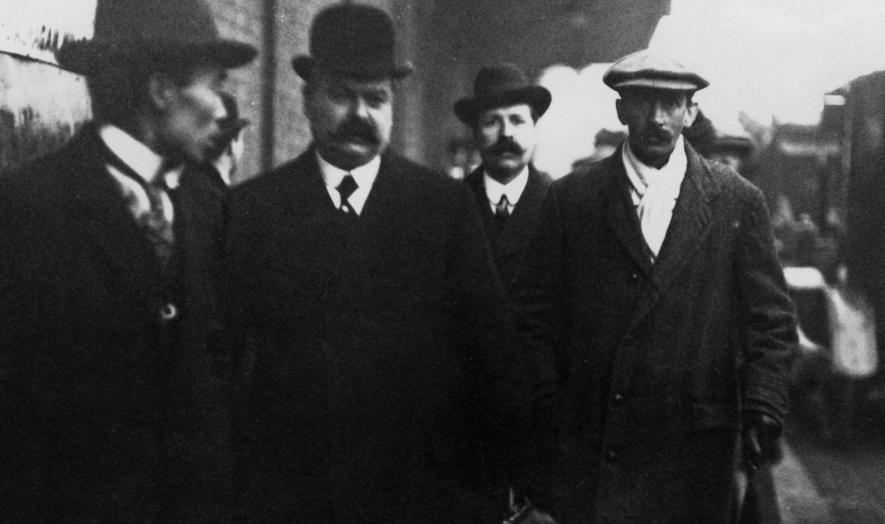 Frank Shackleton (in flat cap, right), older brother of explorer Ernest Shackleton, leaving Waterloo Station with detectives, London, January 1913. Shackleton has just been voluntarily brought back from Portuguese West Africa (now Angola) to answer charges of fraud relating to fictitious companies set up by him. In 1907 he was a suspect in the theft of the Irish Crown Jewels, but later exonerated.