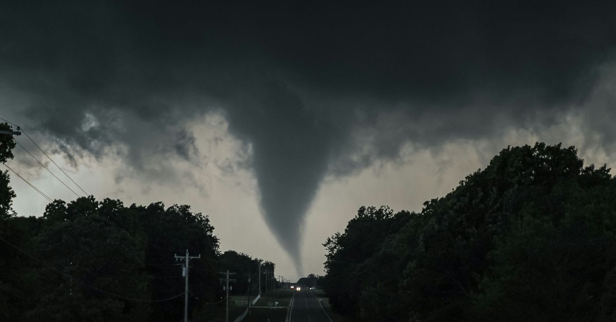 a large tornado is seen in the sky over a road