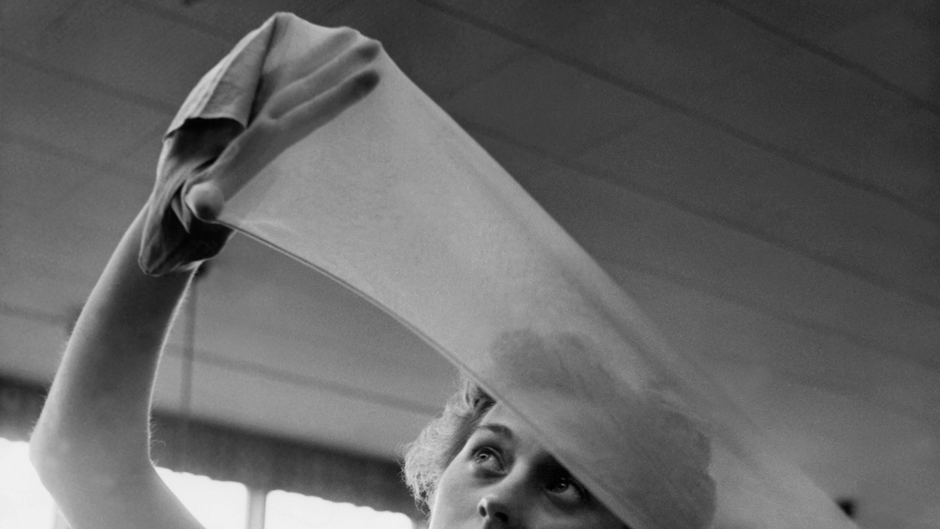Control of nylon stockings at Malmö Strumpfabrik. A woman holds a sock against the light to examine the quality. Subjects: Work, Industry, Fashion, Textile