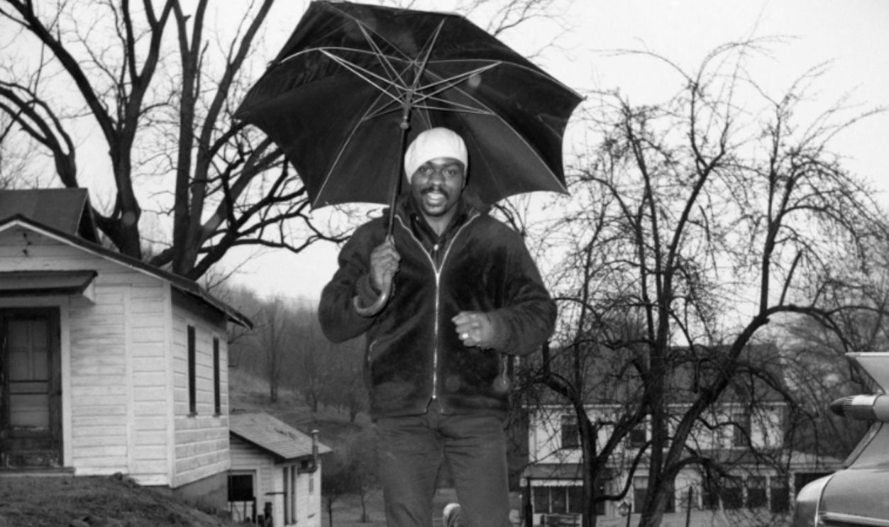 Middleweight boxer Rubin (Hurricane) Carter, protected from rain by huge umbrella, gets in a little roadwork at his training camp here February 10th. Carter is scheduled to meet former welterweight champ Luis Rodriguez in a 10-rounder at Madison Square Garden February 12th.