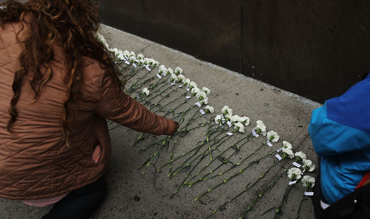 A woman lays a a rose for the victims of the Triangle Shirtwaist Factory fire at a ceremony to mark the 106th anniversary of the tragedy on March 24, 2017 in New York City. On March 25, 1911, 146 factory workers, primarily young immigrant women, lost their lives during a fire in which many had to jump from the upper floors of the factory. The fire helped to usher in the modern labor movement and new workplace safety laws.