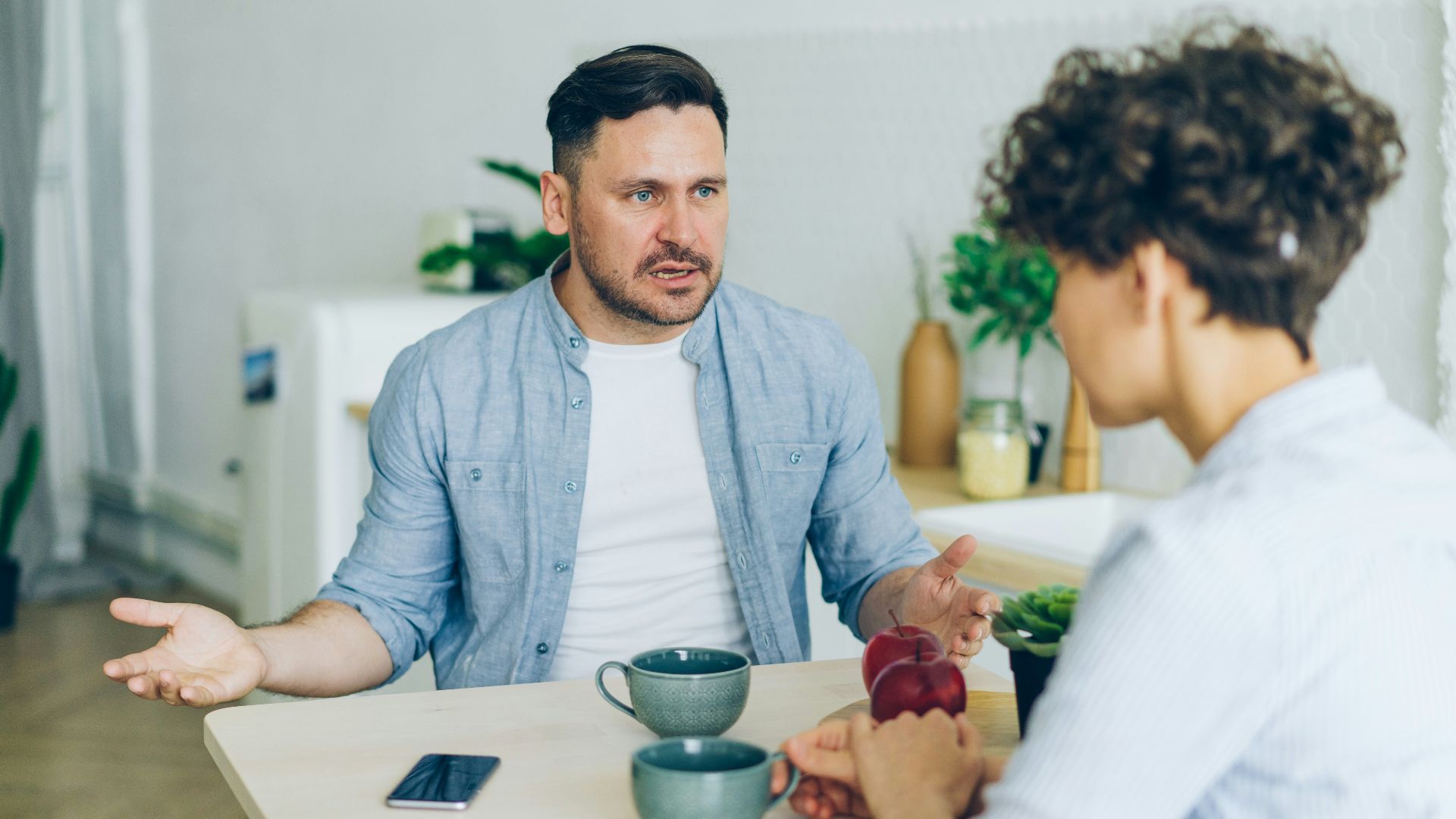 a man sitting at a table talking to a woman