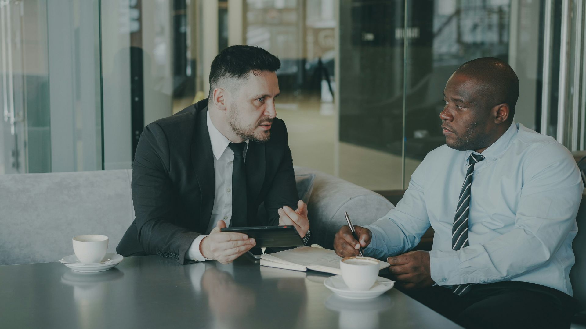 Two businessmen discussing work over coffee.