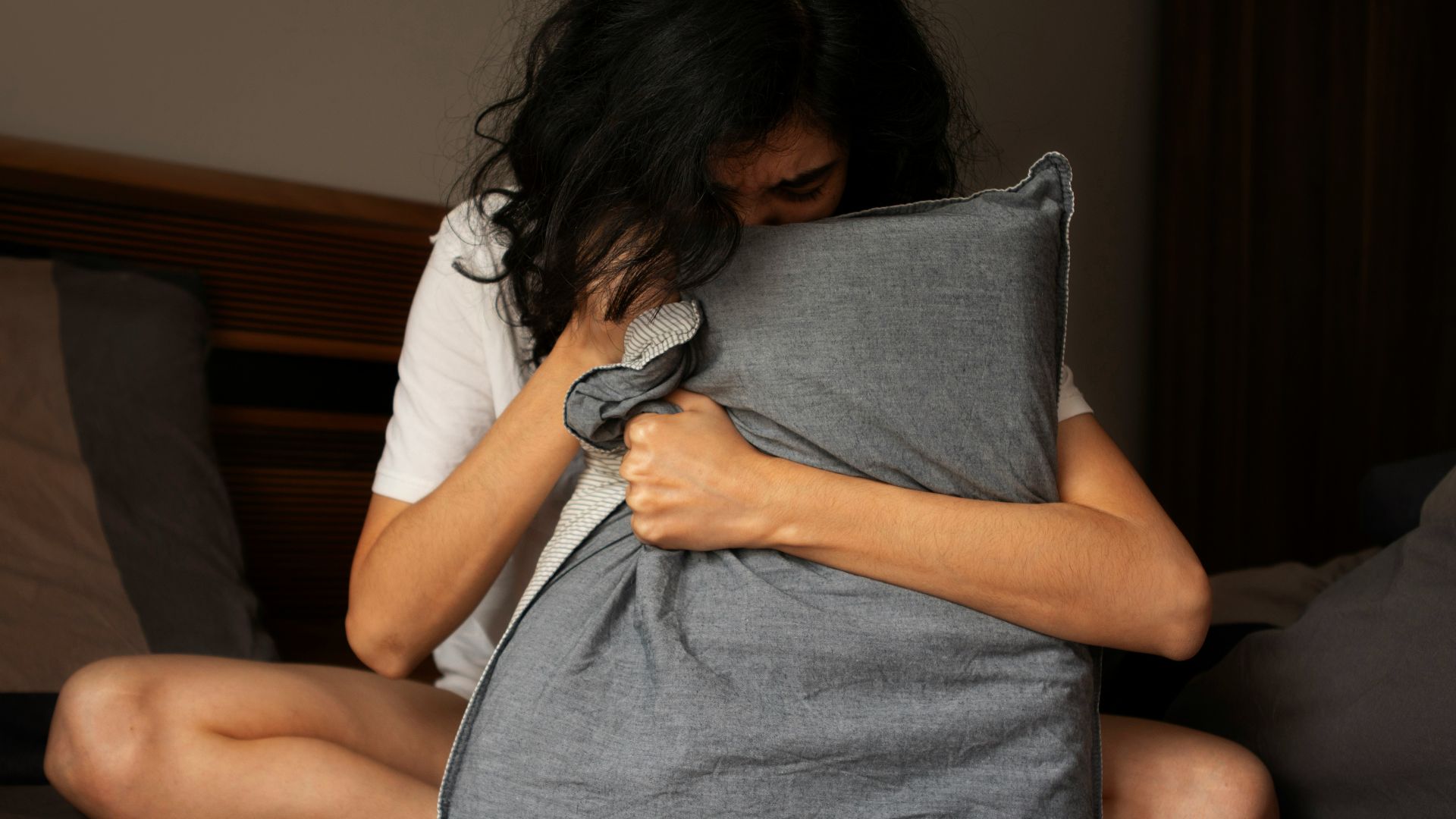 A woman sitting on a bed holding a pillow