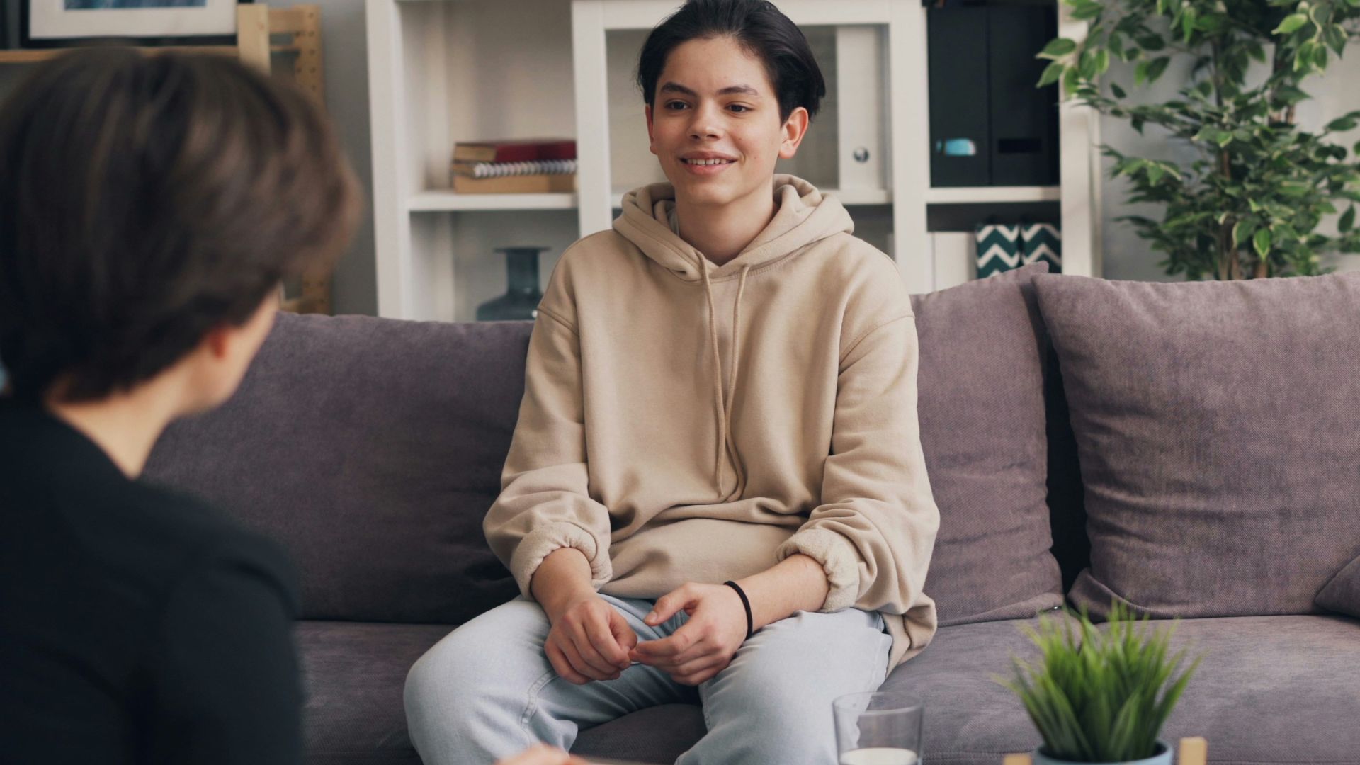 a woman sitting on a couch talking to another woman