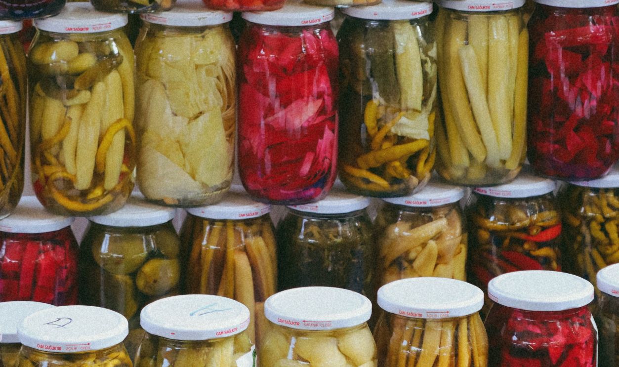 Vibrant display of pickled vegetables in jars at a traditional Turkish market