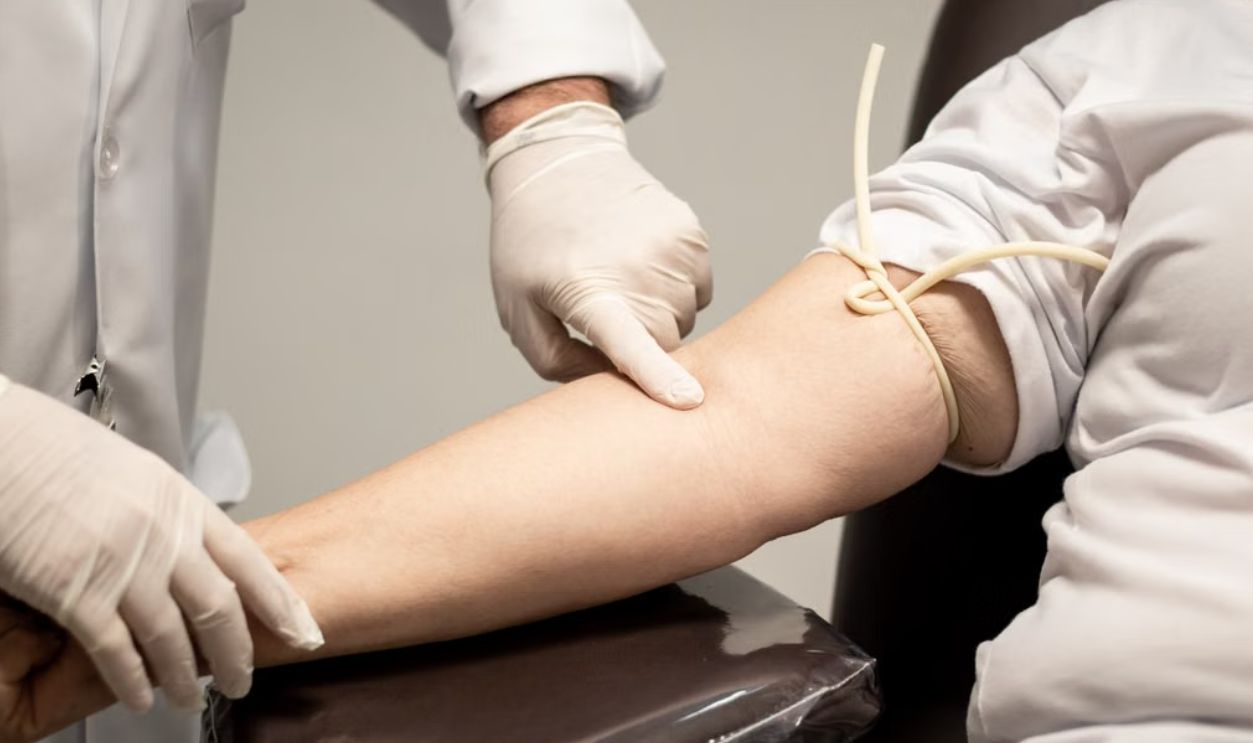 Medical professional wearing gloves preparing patient for blood draw using a tourniquet