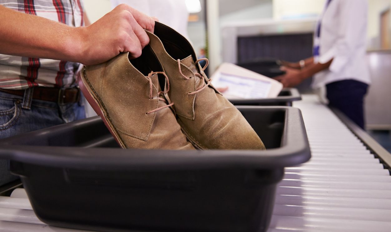Man Putting Shoes Into Tray For Airport Security Check