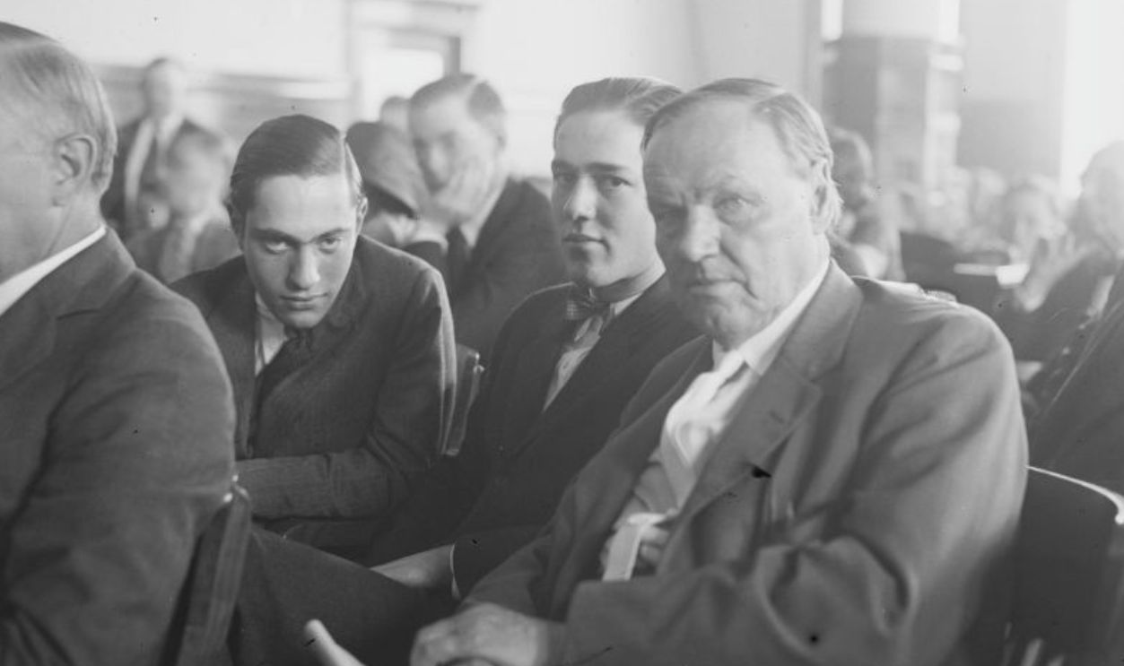 Richard Loeb, Nathan Leopold Jr, and Clarence Darrow, looking toward the camera and sitting in a crowded courtroom during the Leopold and Loeb murder trial, Chicago, Illinois, July 24, 1924.