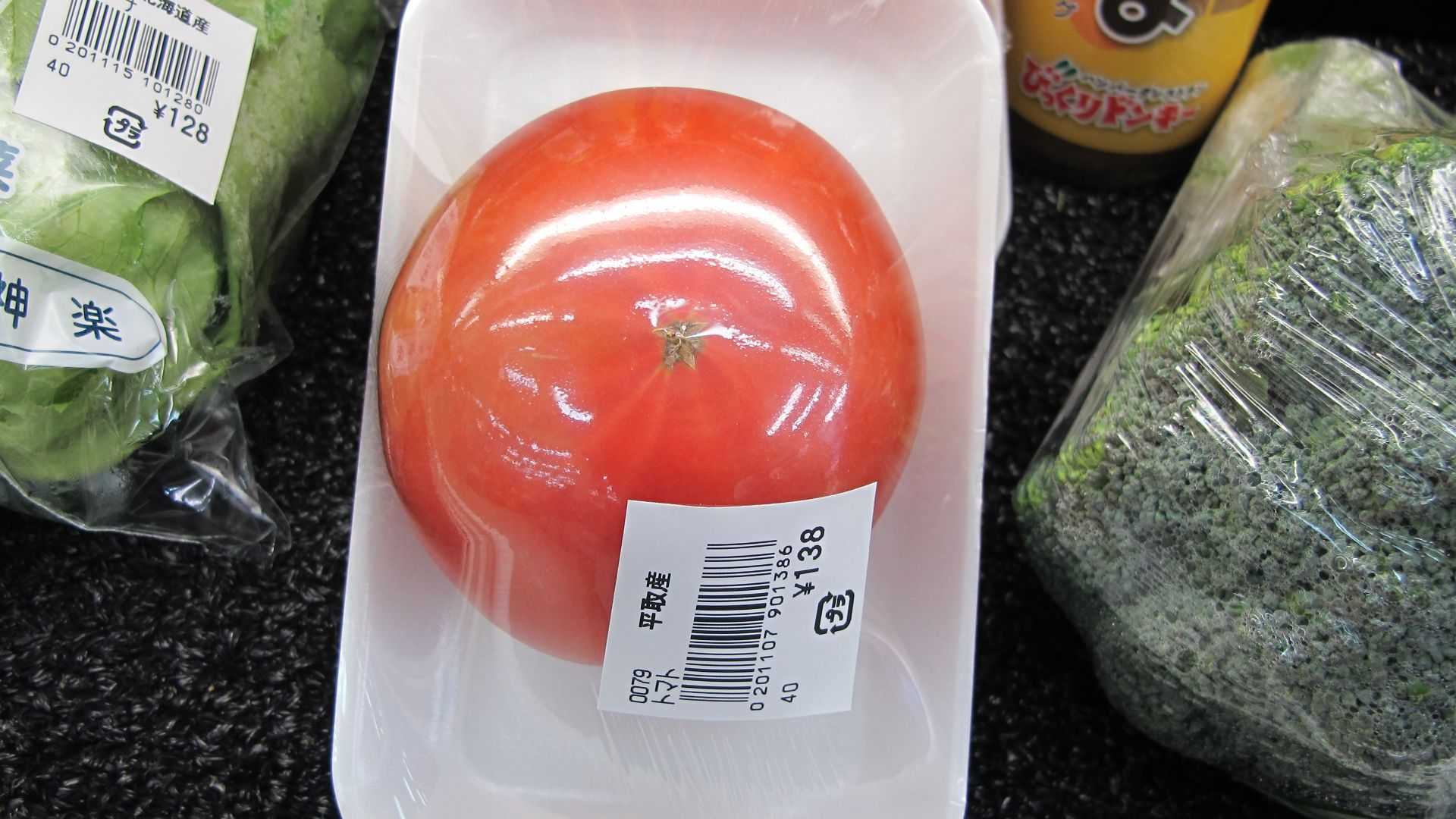 Wasteful food packaging in Japan. A single tomato covered in plastic wrap on a styrofoam tray.