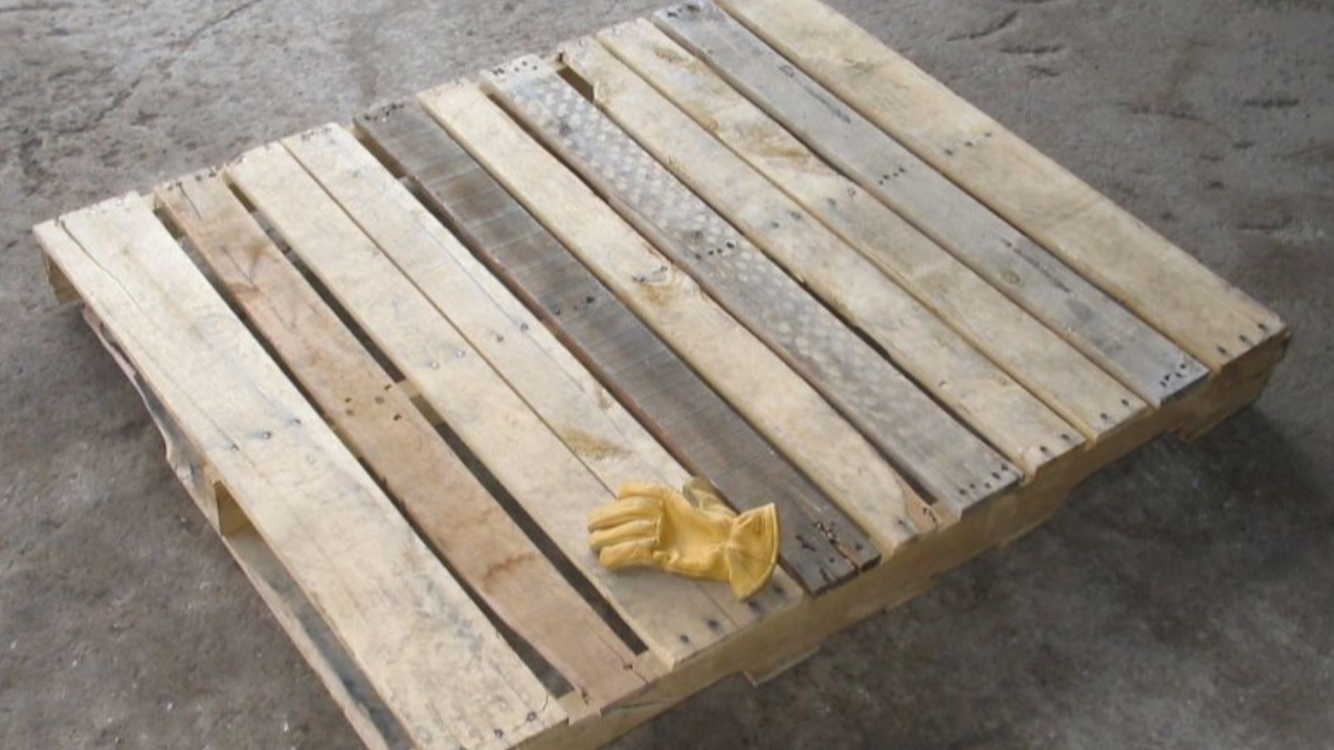 A wooden pallet measuring 4 feet (1.2 m) by 40 inches (1.0 m) by 5 inches (13 cm). The glove is a lined elkskin work glove, size Medium.