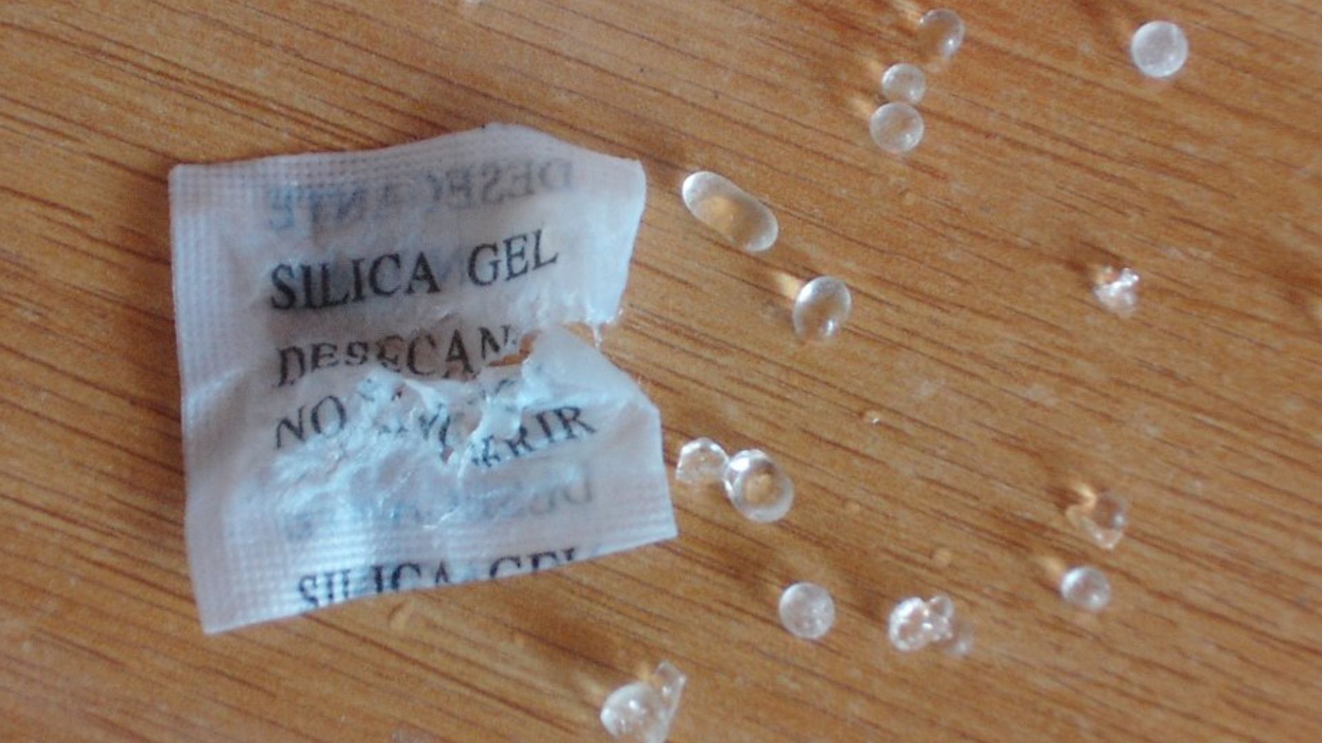 Una bolsa desecante con las bolitas de gel de sílice que llevaba dentro. Hay algo de agua por la mesa.

Autor: Daniel Clemente
Dominio público