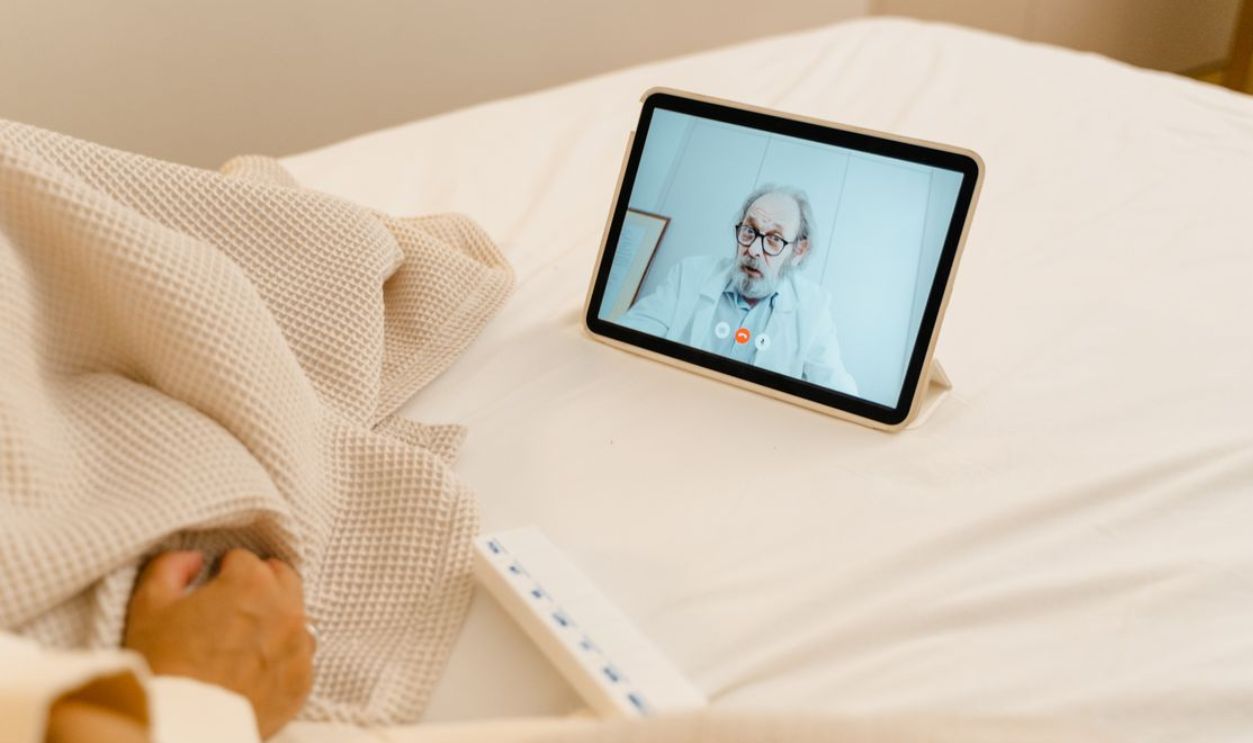 Patient in bed having a virtual consultation with a doctor via tablet