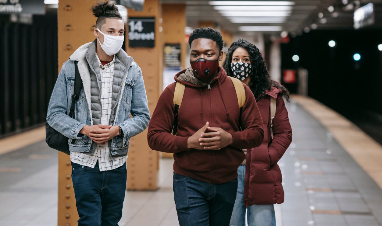 A group of diverse young adults wearing masks at a subway station during COVID-19
