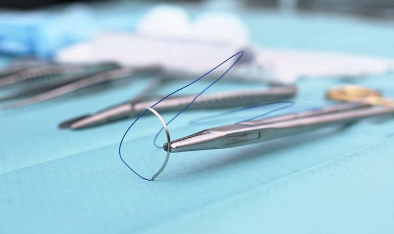 Surgical thread for sewing close up view. Medical equipment for suturing wound. Surgeons tools icons set on blue background. Medical and surgery concept