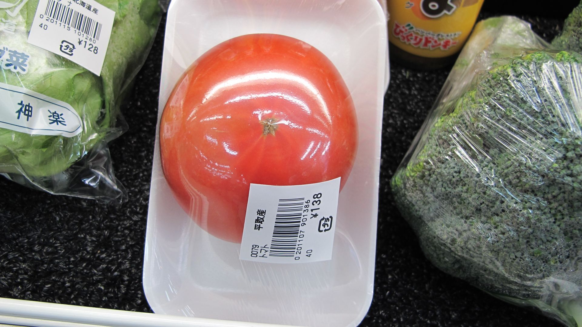 Wasteful food packaging in Japan. A single tomato covered in plastic wrap on a styrofoam tray.
