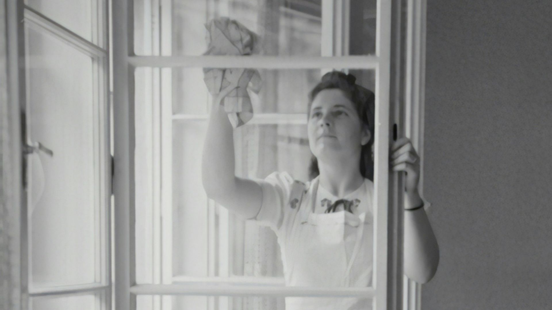 grayscale photography of woman cleaning glass window