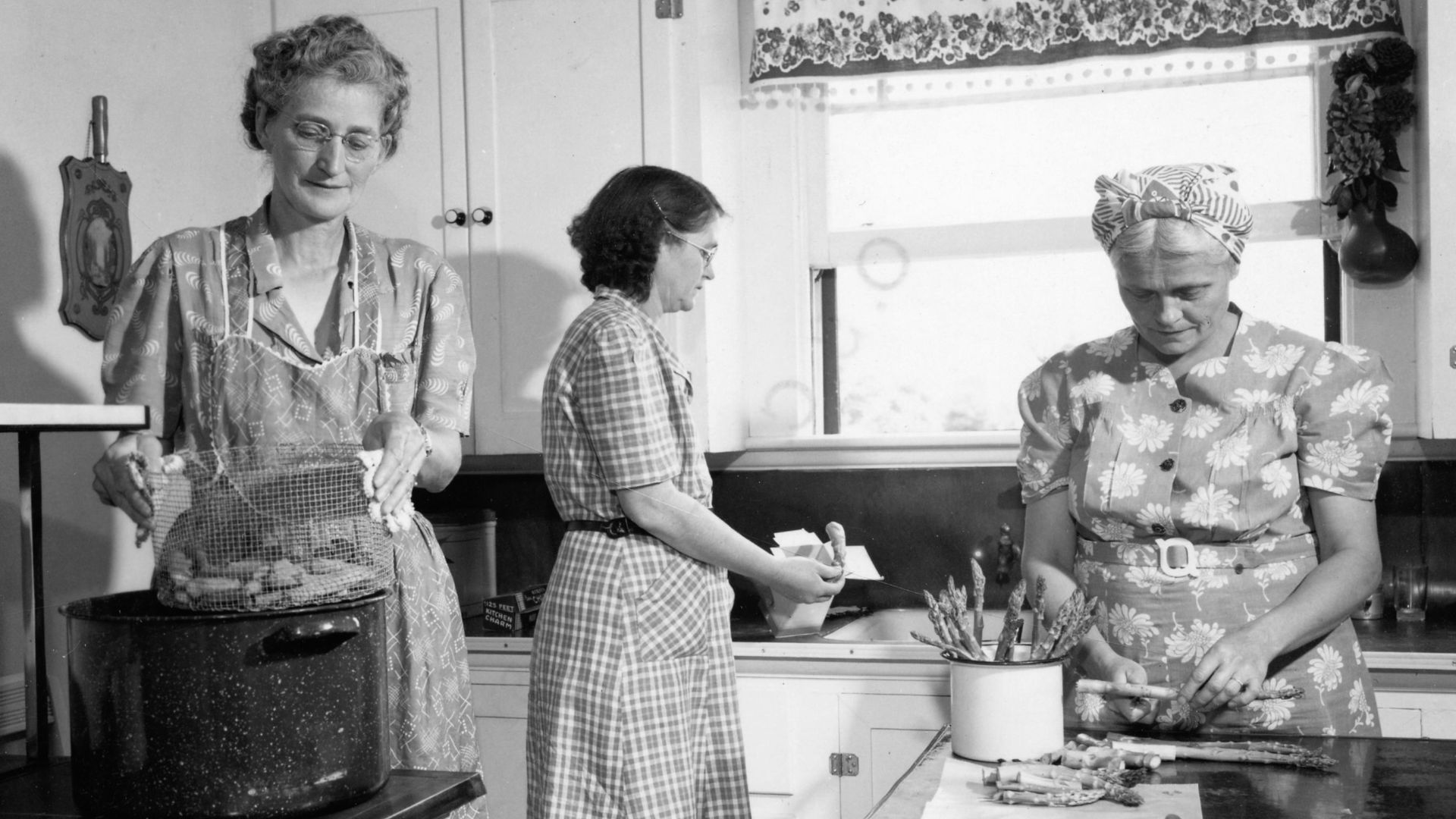 Three women working together in a vintage kitchen.