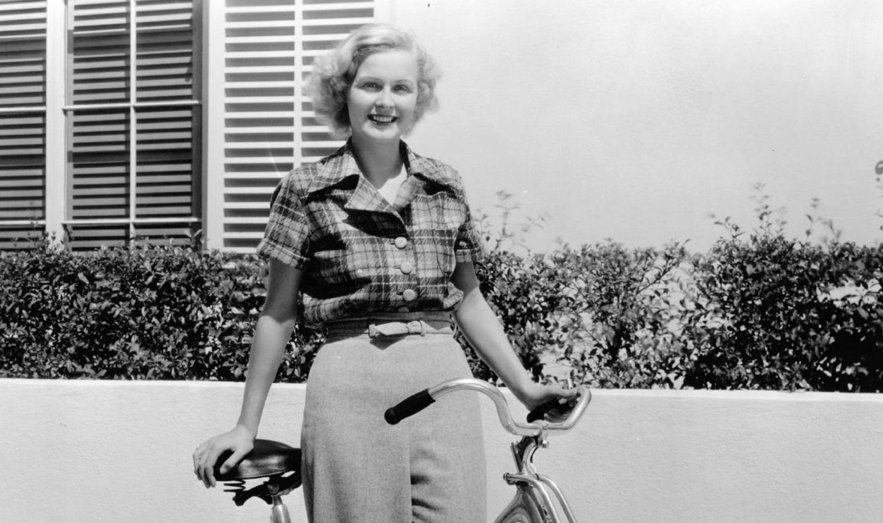circa 1938: Gloria Stuart, the stage name of Gloria Stuart Finch ( 1909 - ) the American leading lady of the thirties is pictured with the bicycle that she regularly rides around the Century Fox studio between takes on her film.
