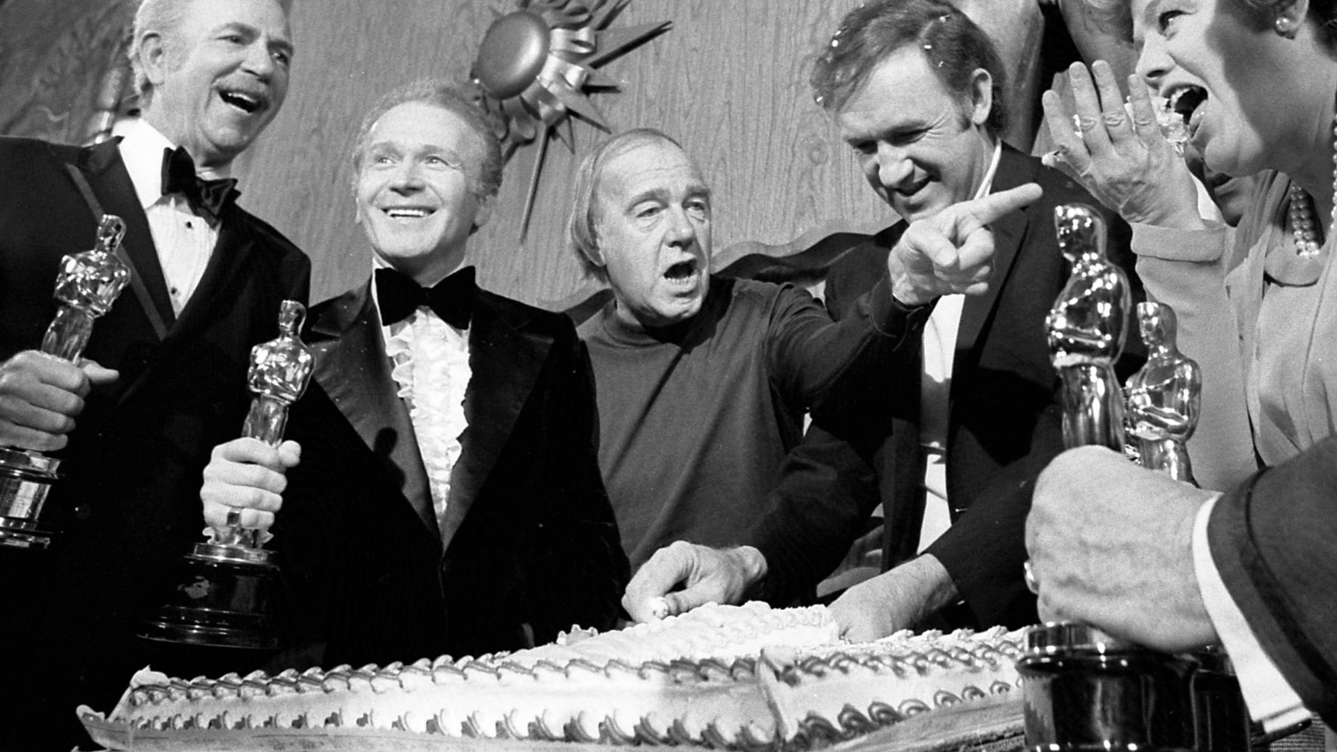 Academy Award winner Gene Hackman cuts cake on set of his new film, The Poseidon Adventure, at 20th Century Fox. Other members of cast who previously had won Oscars join in celebration. From left are Jack Albertson, Red Buttons, Ronald Neame (director), H