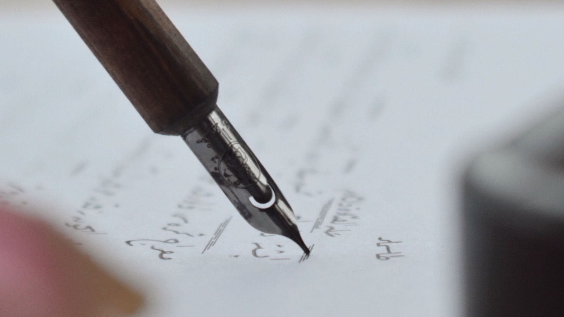 A detailed shot of a fountain pen writing elegant cursive script on paper.